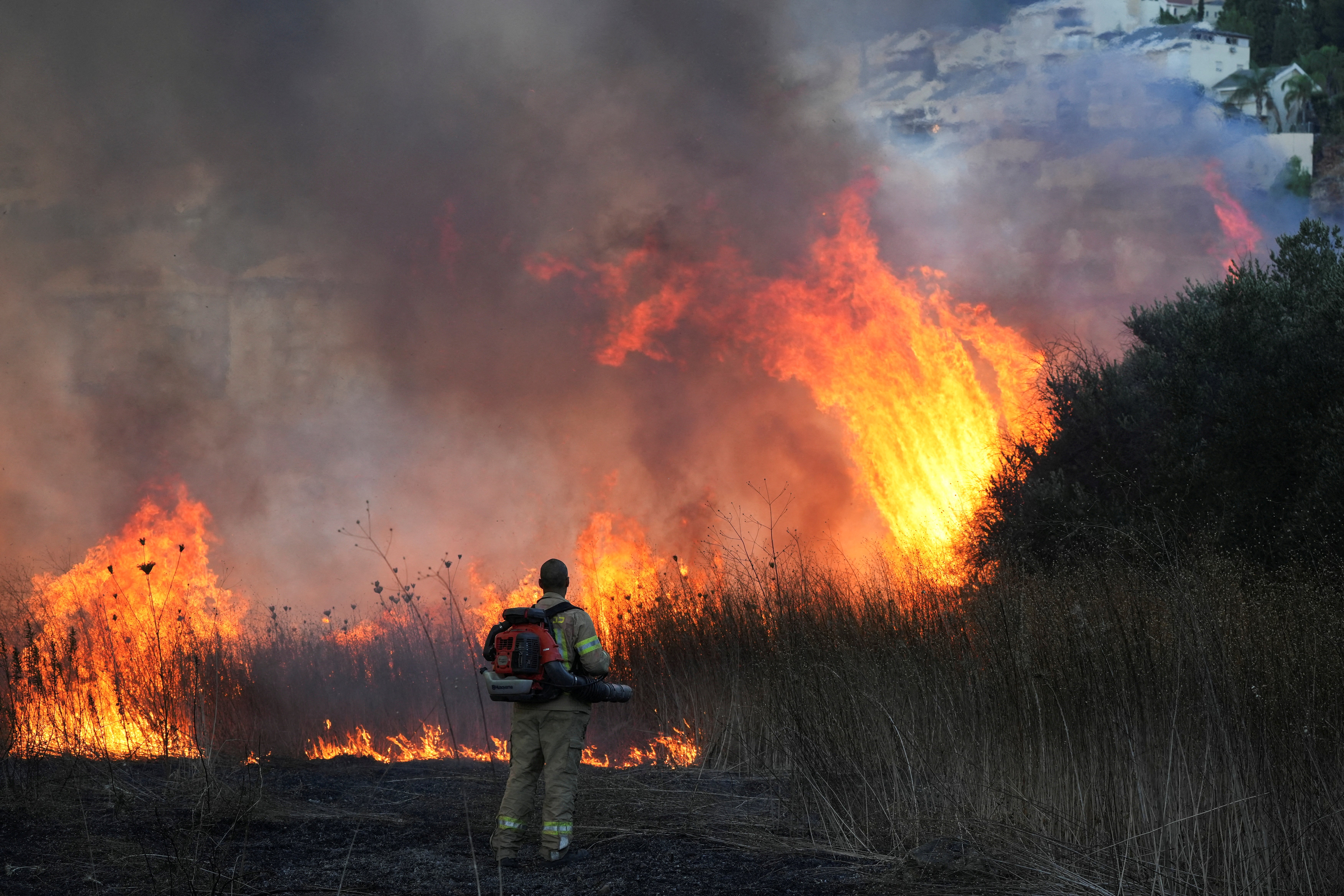 A firefighter works to put out a blaze after rockets were fired from Lebanon towards Israel, amid cross-border hostilities between Hezbollah and Israel, in Kiryat Shmona