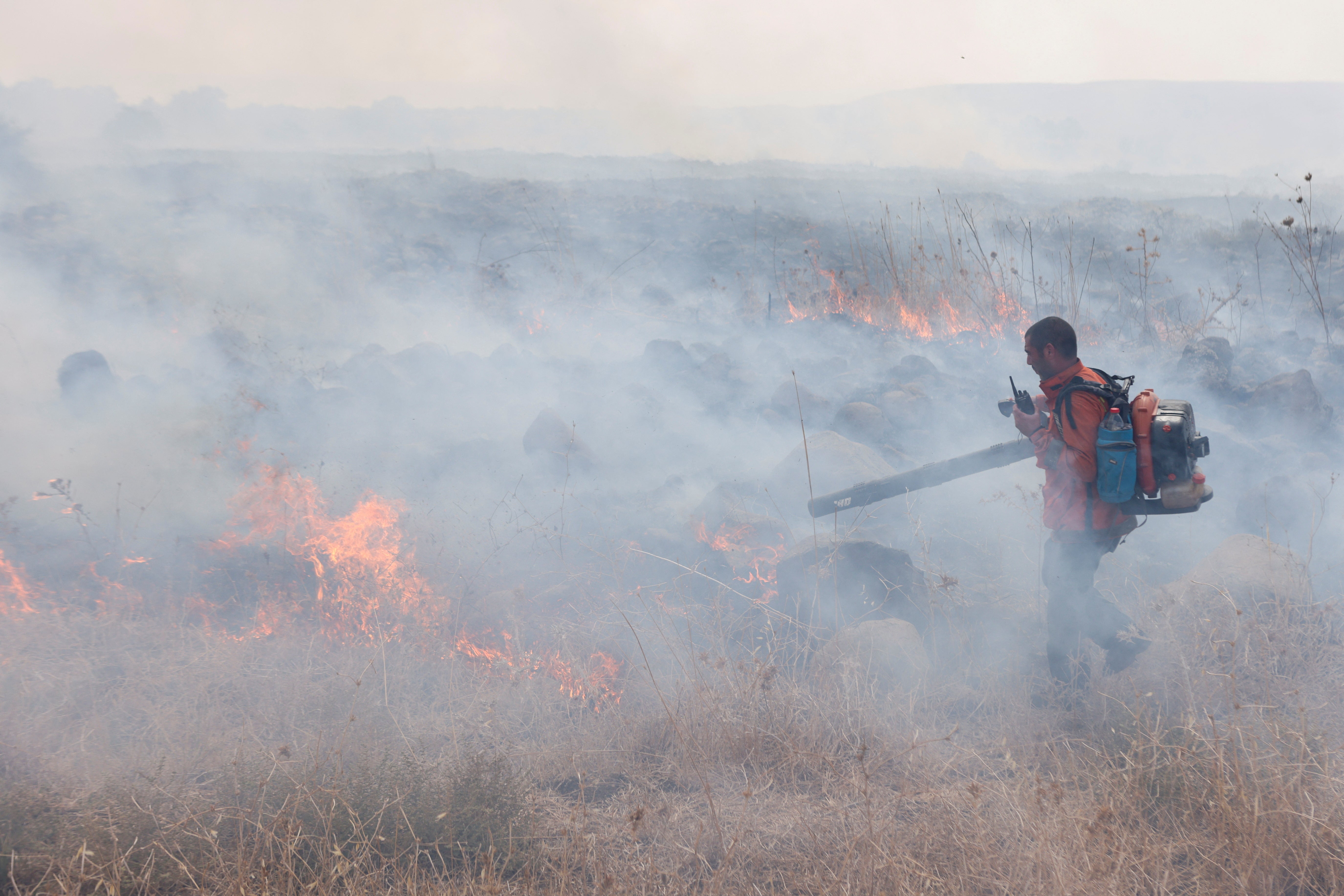 Pictured: An Israeli extinguishes flames following a rocket attack from Lebanon