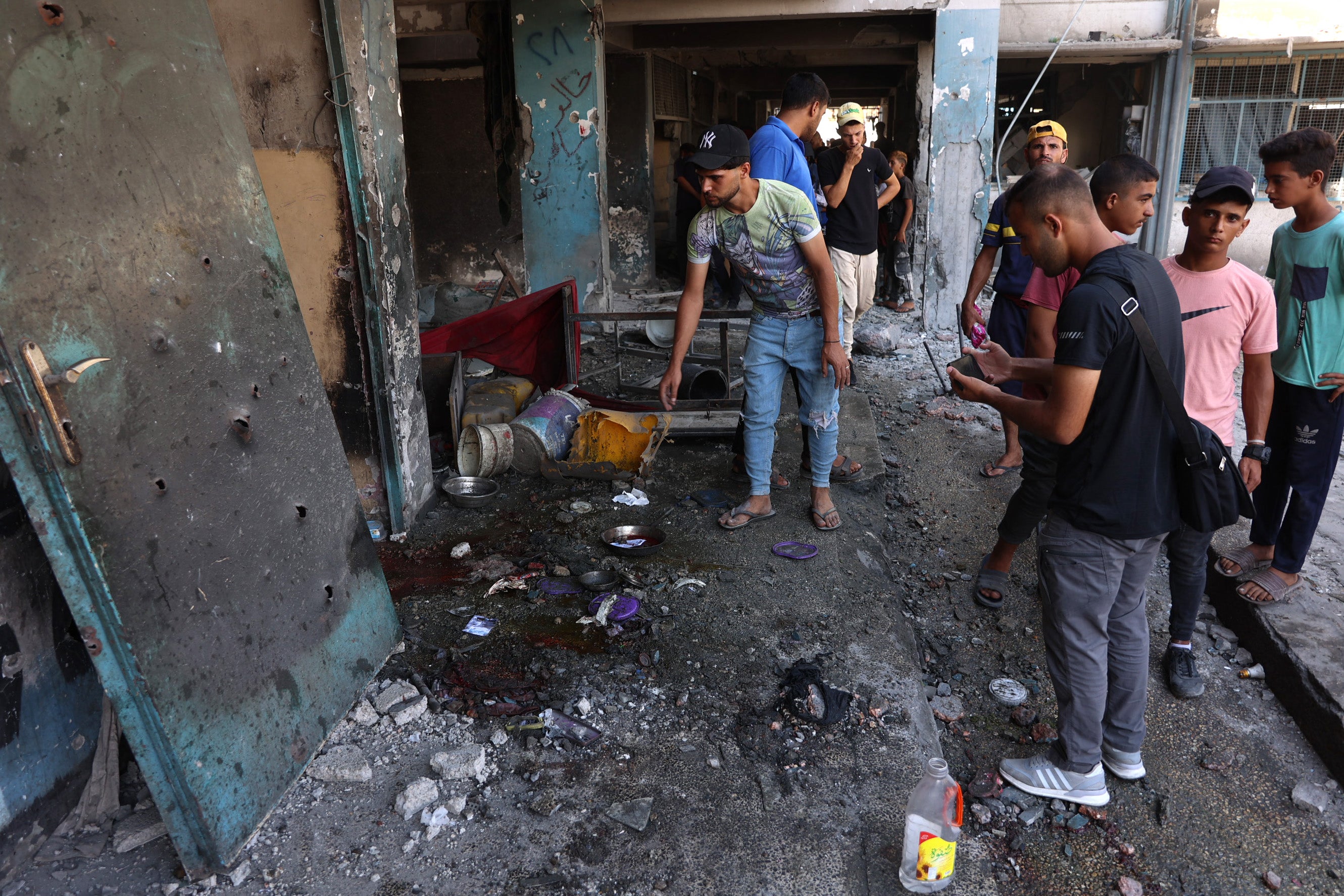 A group of Palestinian men look over the damage following an Israeli airstrike on a school in Gaza