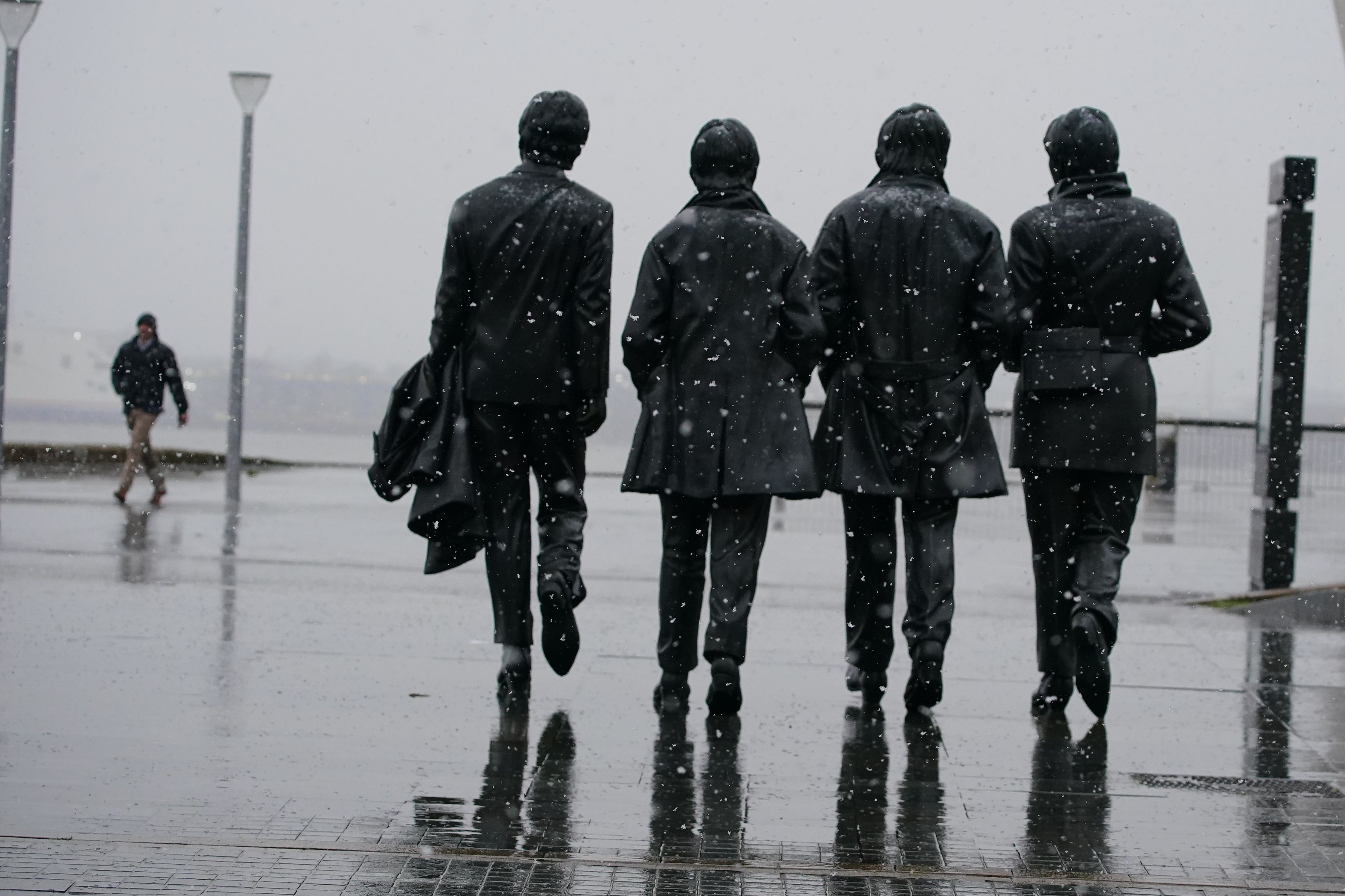 Snow falls around the Beatles statue at Pier Head in Liverpool (Peter Byrne/PA)