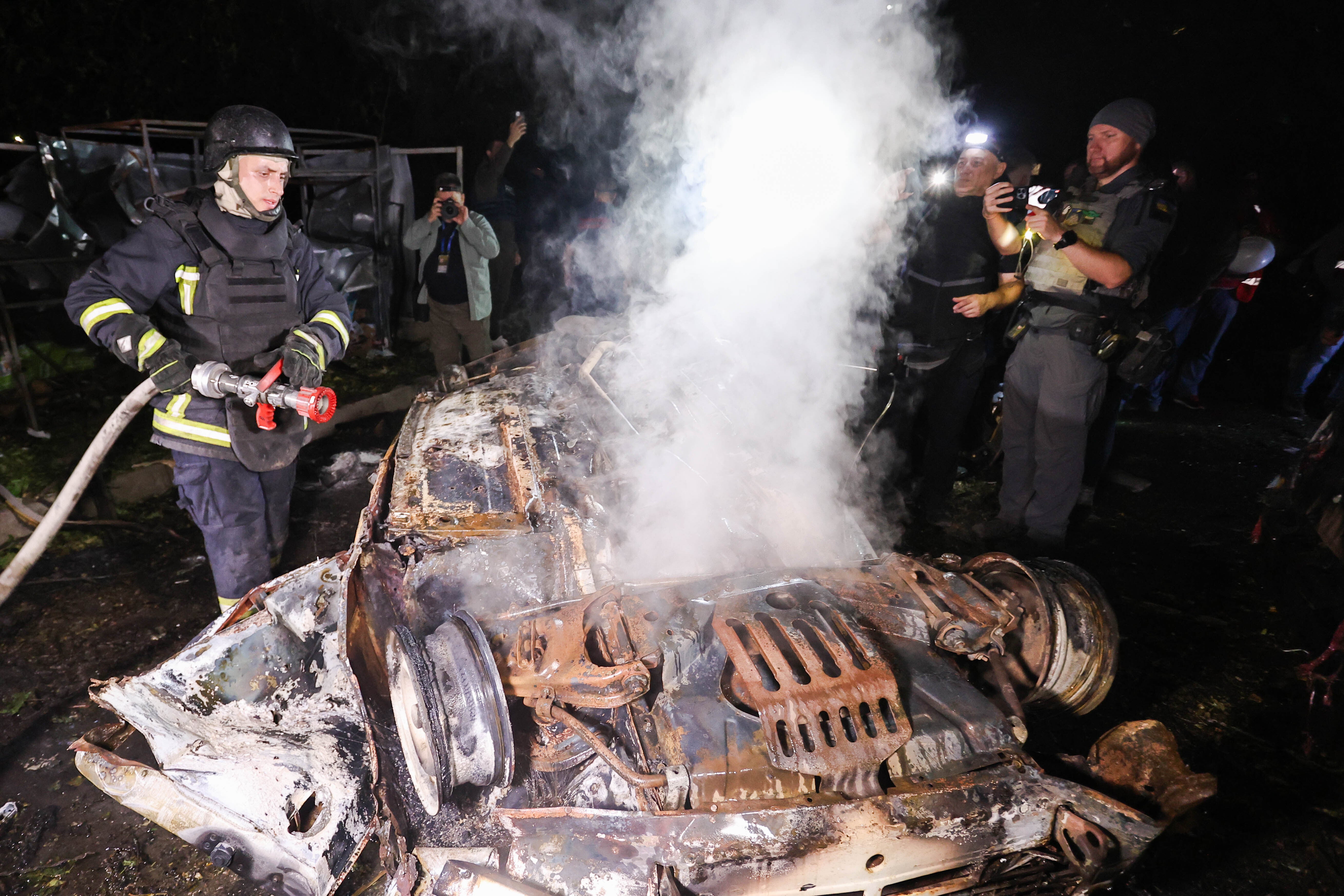 Firefighters put out a fire on a destroyed car