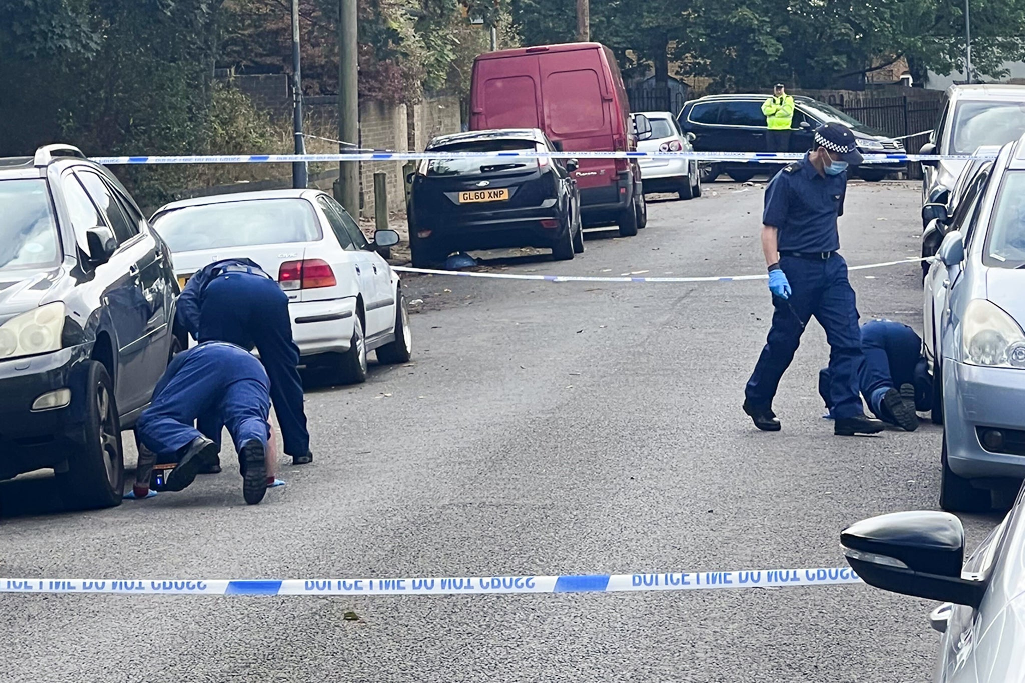 Forensic officers were seeing searching underneath cards on Eglinton Road, Woolwich, a day after the stabbing