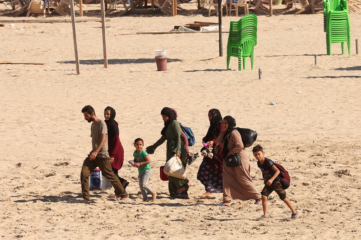 People carry belongings at a beach as they flee southern Lebanon