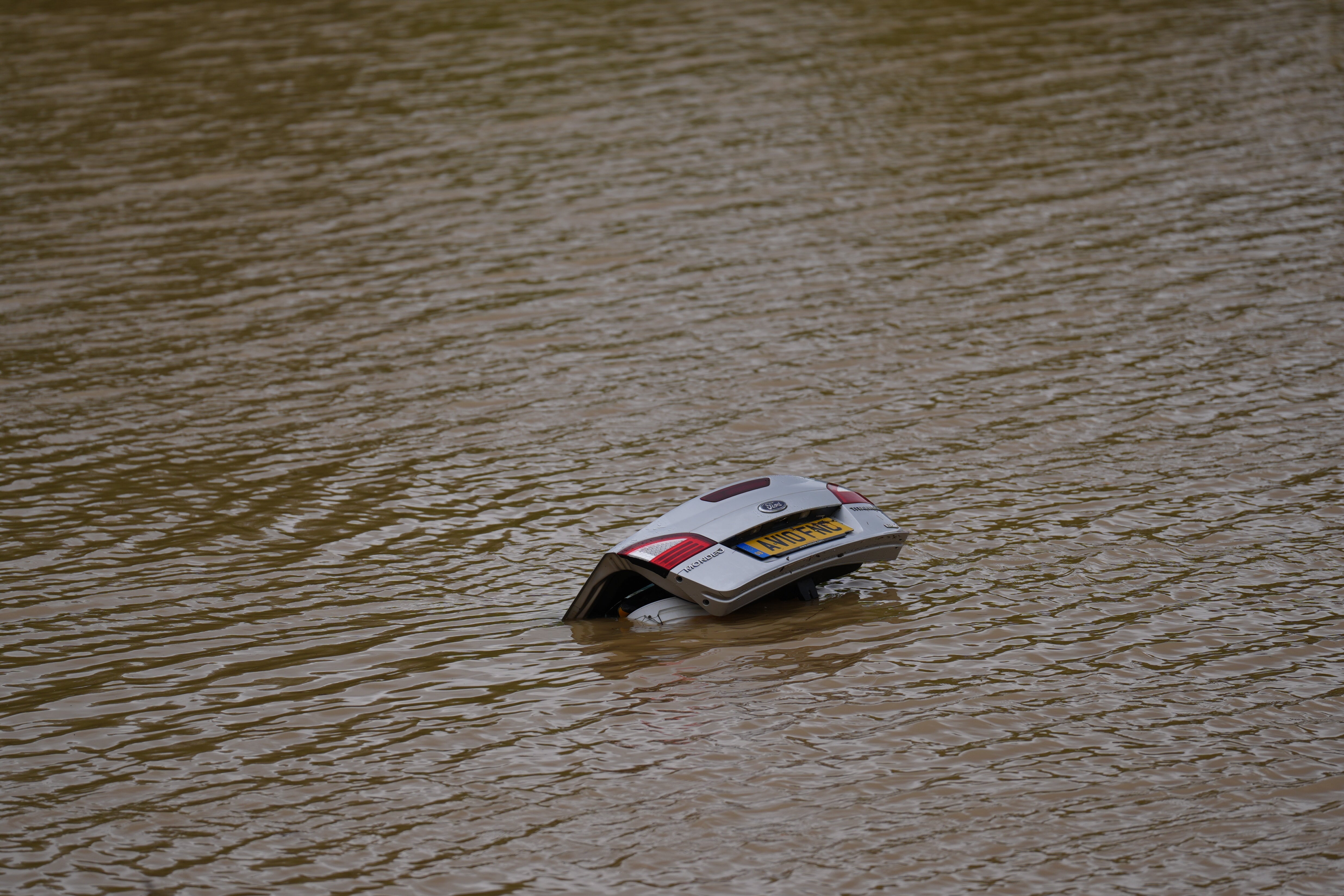 The open boot of a car is visible in the floodwater on the A421