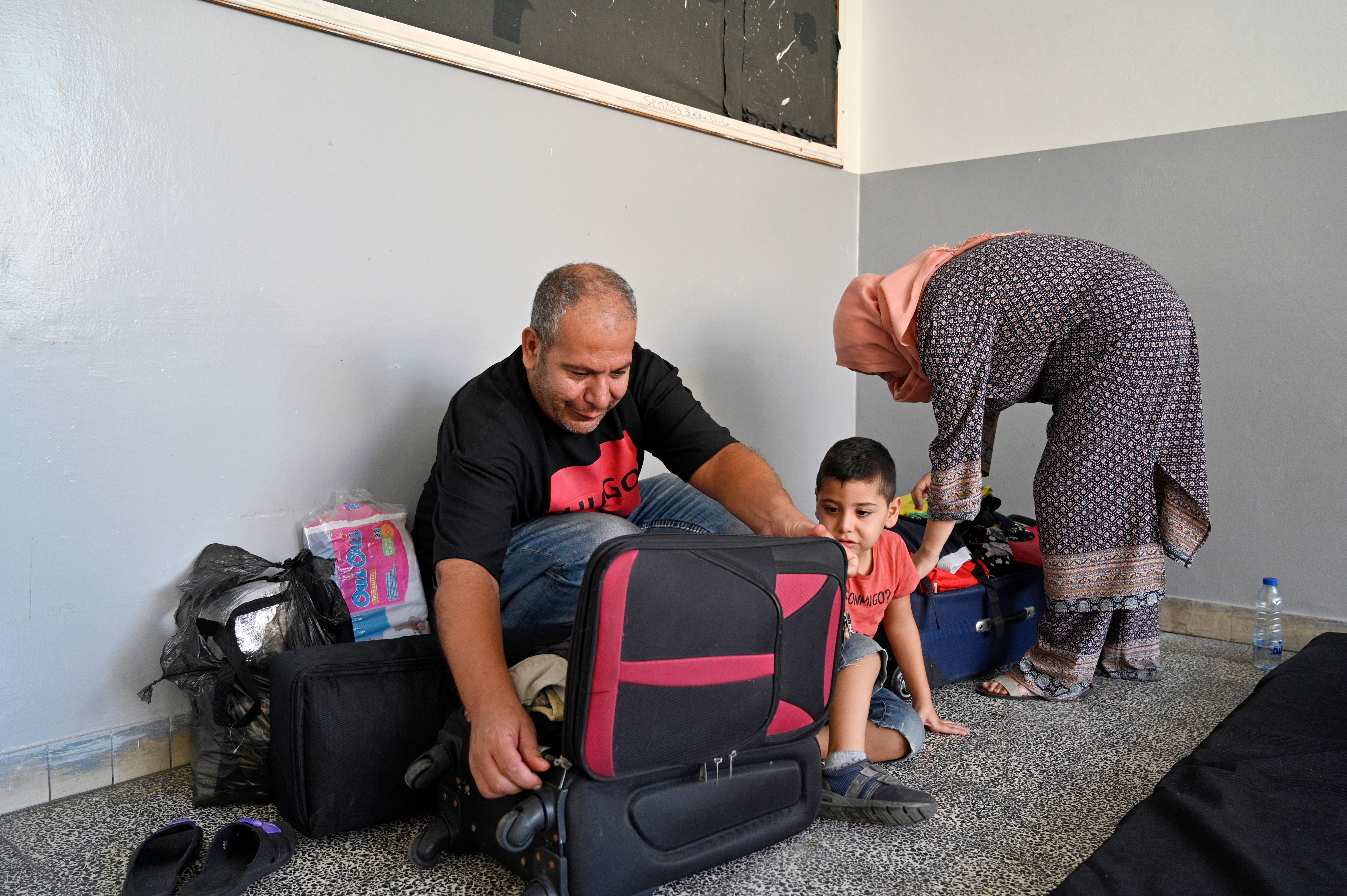 A family unpacks their belongings at a makeshift shelter after fleeing southern Lebanon