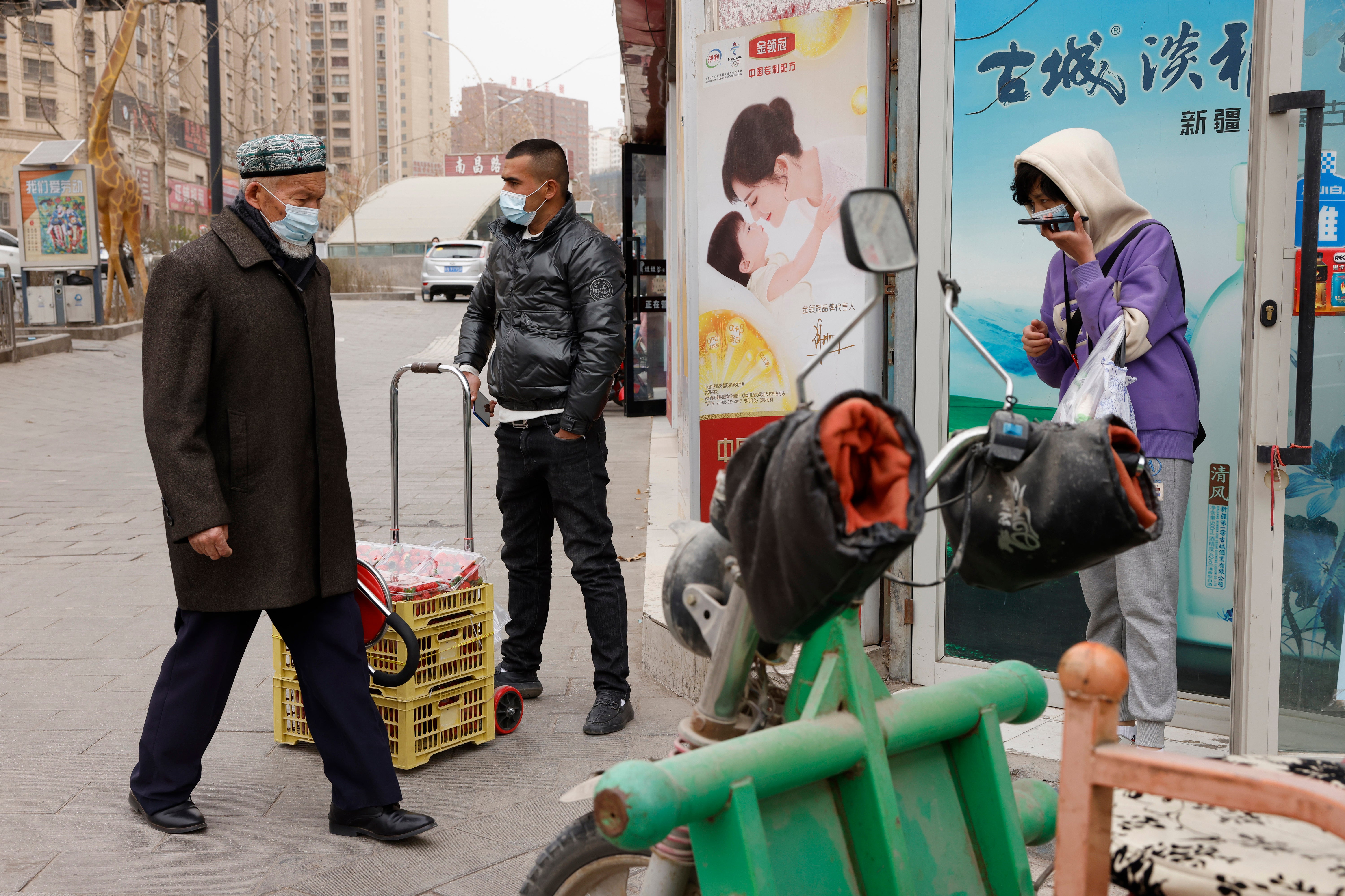 In this 18 March 2021 file photo, residents wearing masks walk along the streets of Aksu in western China's Xinjiang region