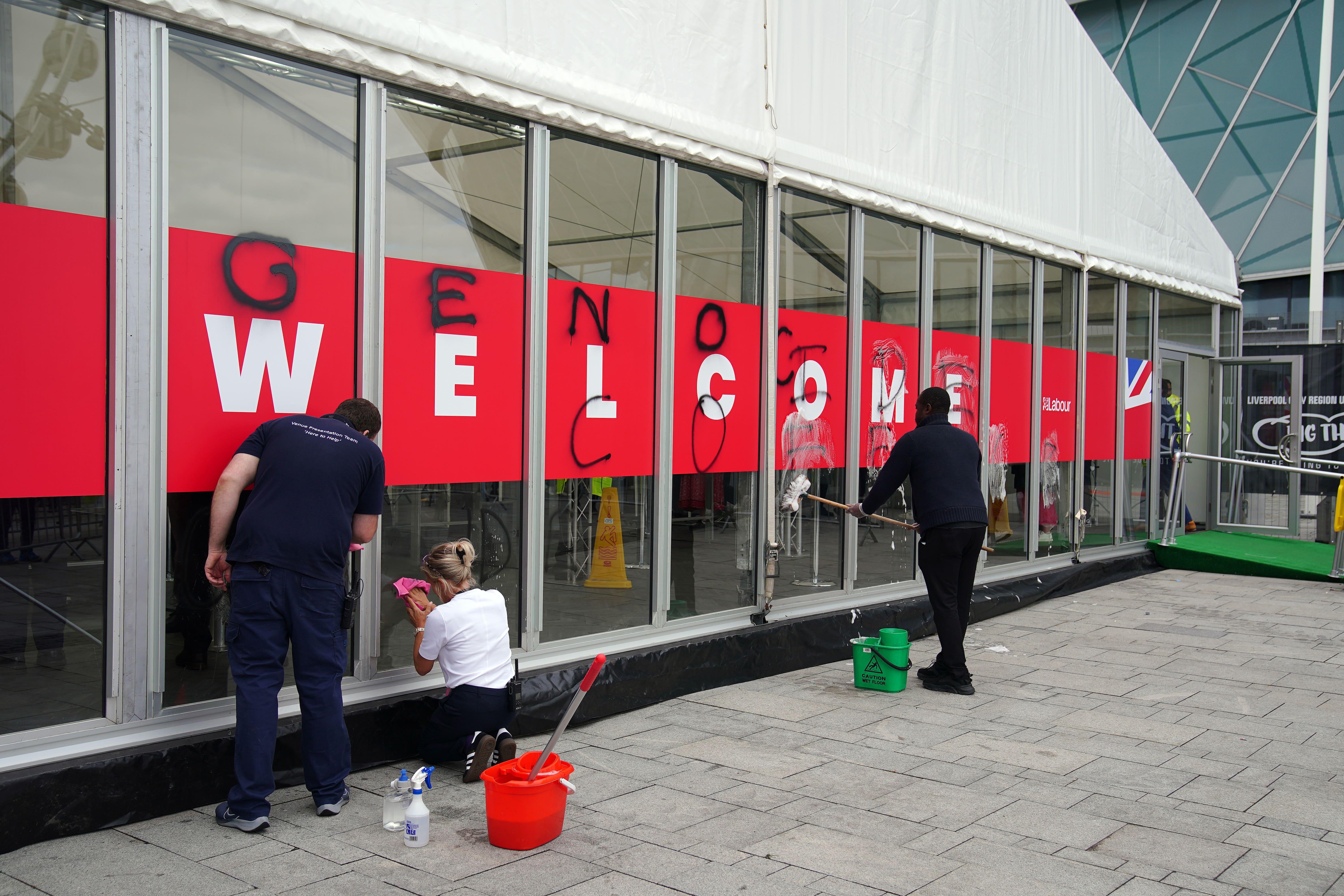 People working to remove graffiti sprayed by Youth Demand on the security check-in building at the Labour Party conference (Peter Byrne/PA)