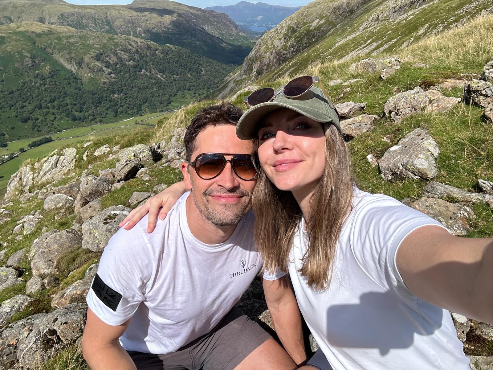 James and his girlfriend Rachel smiling at the camera against a backdrop of a mountain