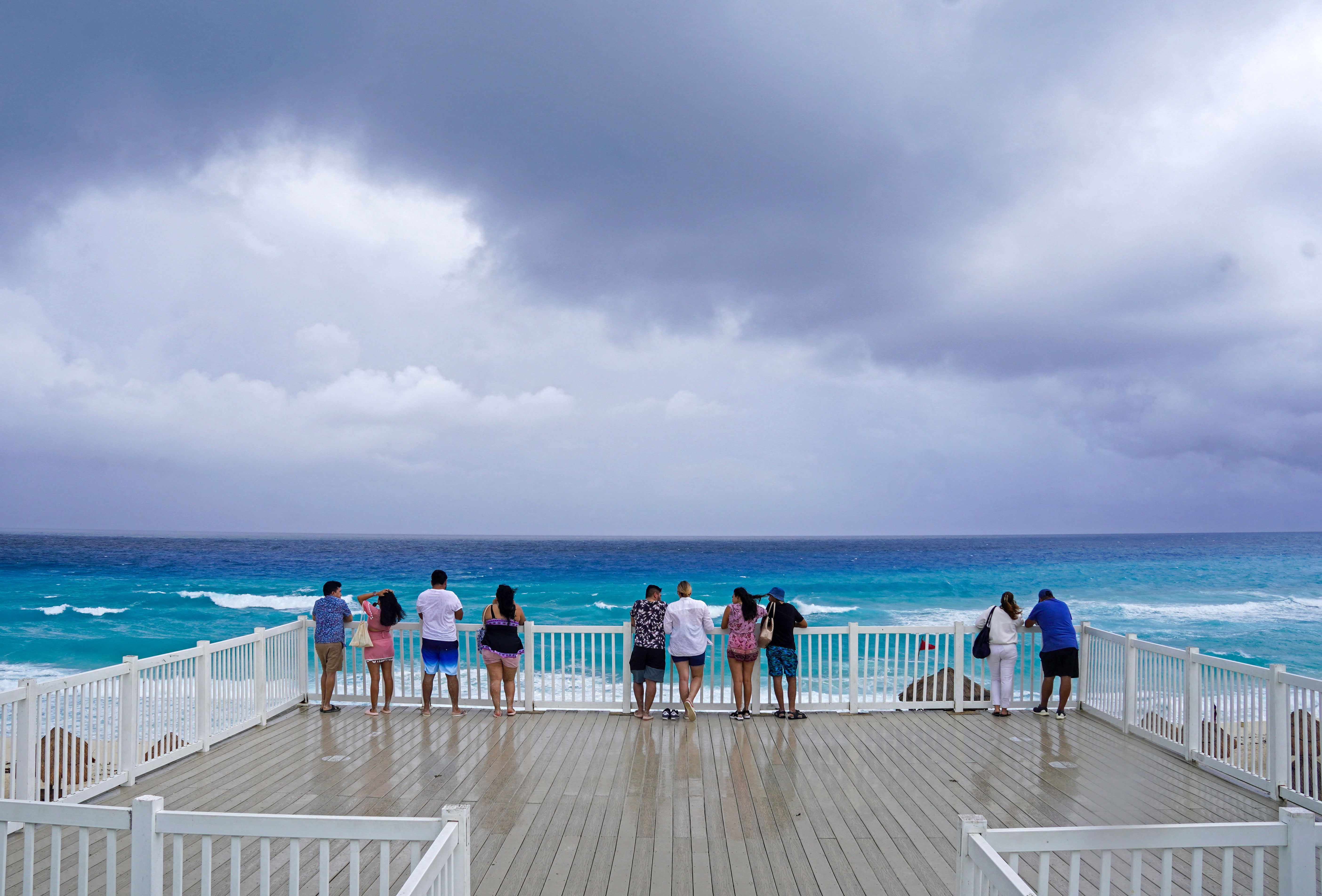 Beachgoers look at the sea on the beachfront ahead of the arrival of tropical storm Helene in Cancun on Tuesday