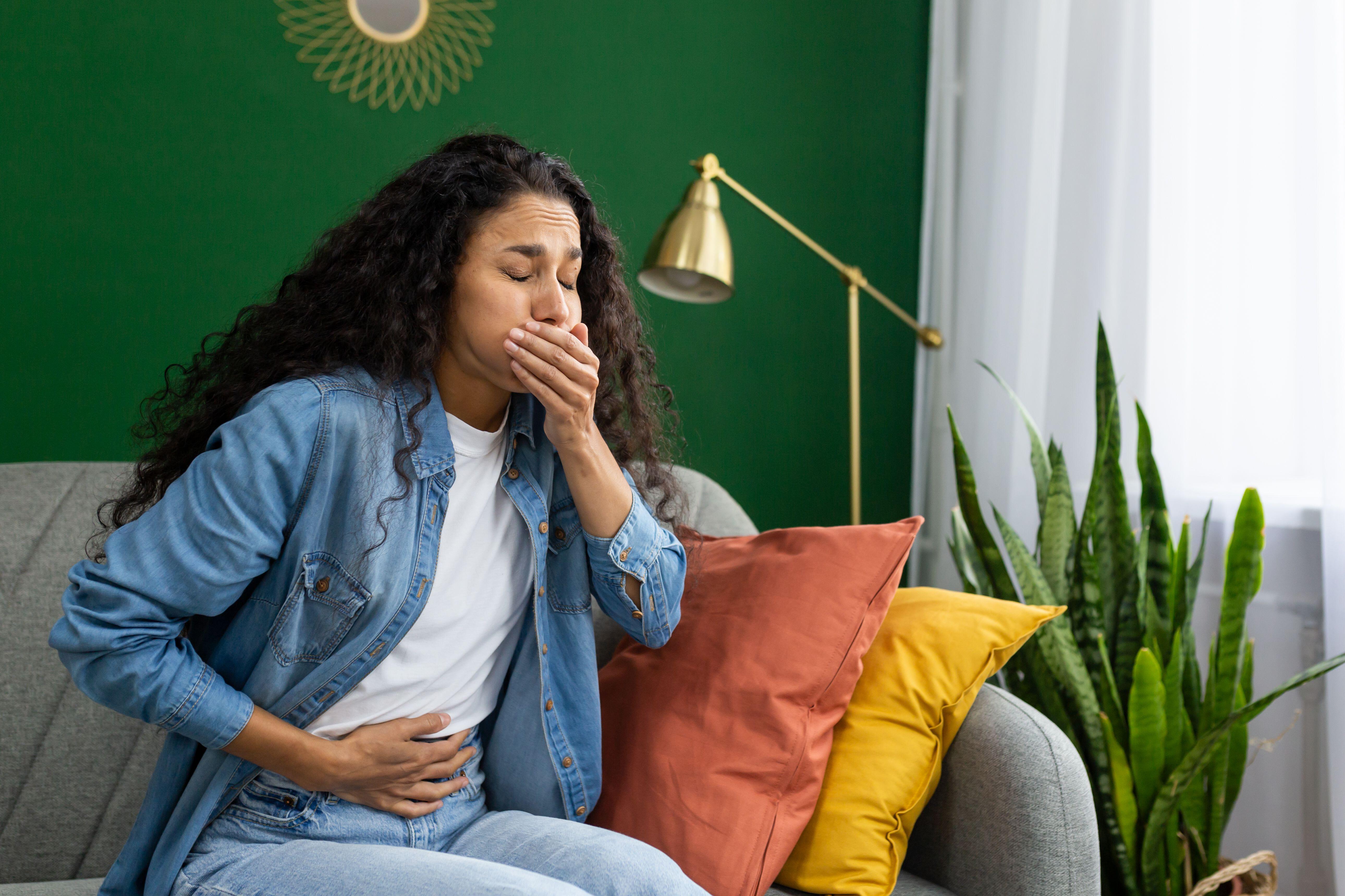 A young woman feeling nauseous on a couch