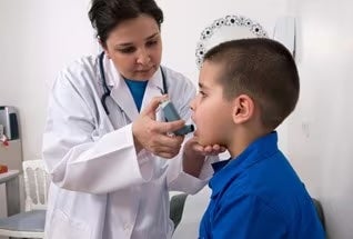 A doctor uses an inhaler on a little boy with asthma. Children with asthma are particularly susceptible to EV-D68.