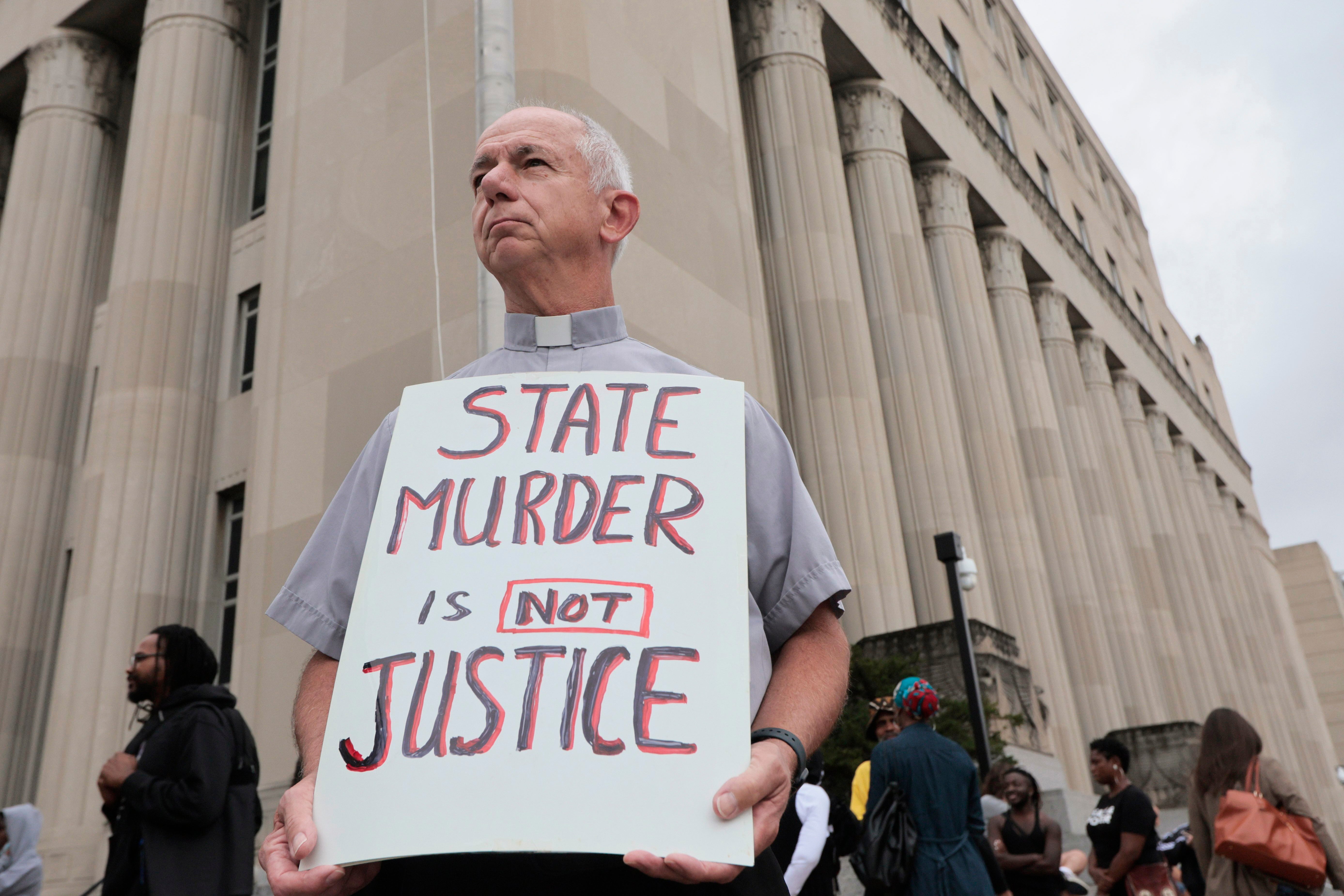 Deacon Dave Billips, with the Office of Peace and Justice with the St. Louis Archdiocese, holds a sign as he stands with protesters holding space to halt the execution of Marcellus Williams on Sept. 24