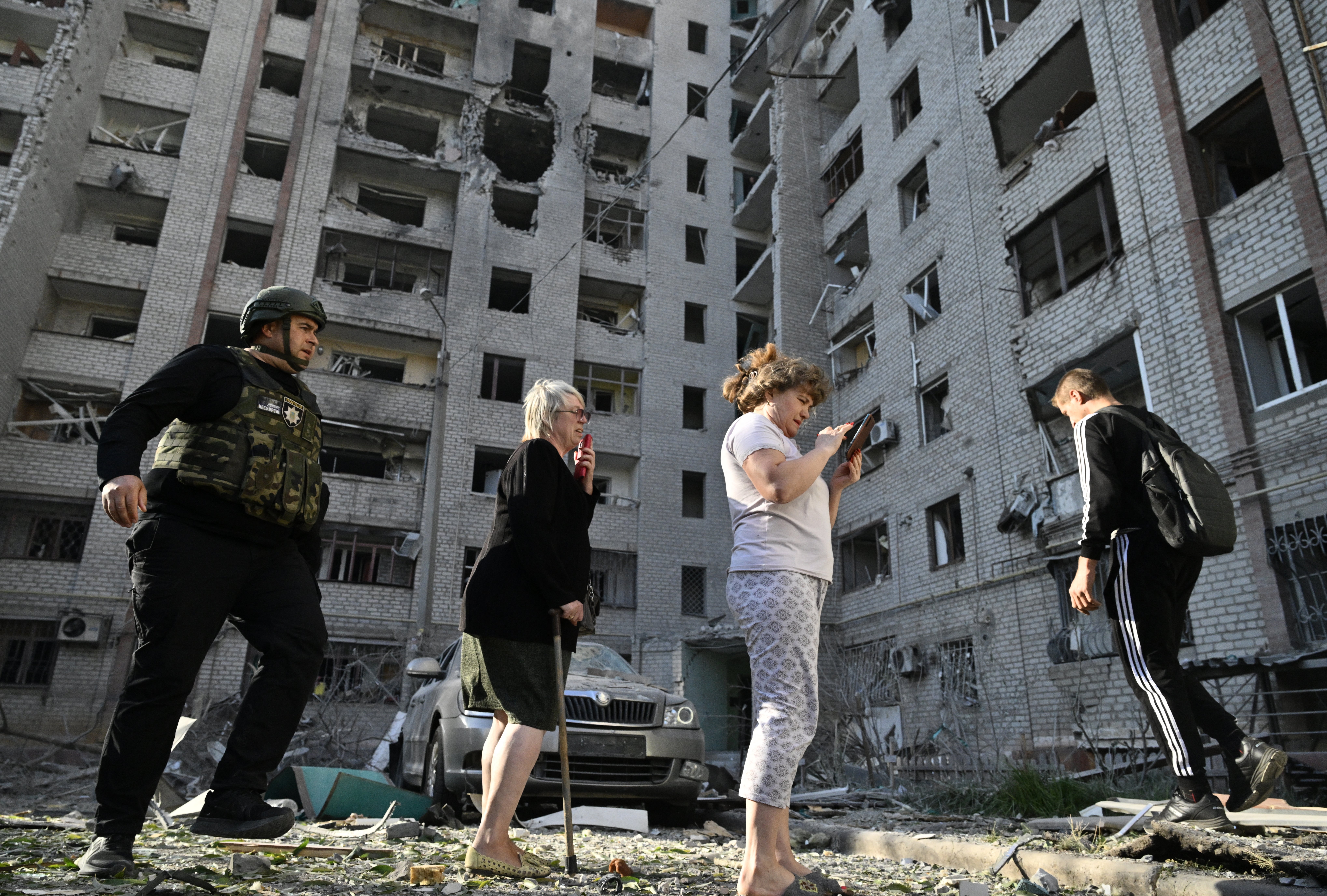 Local residents stand in front of a damaged building following a Russian strike in the city of Kramatorsk, Donetsk region