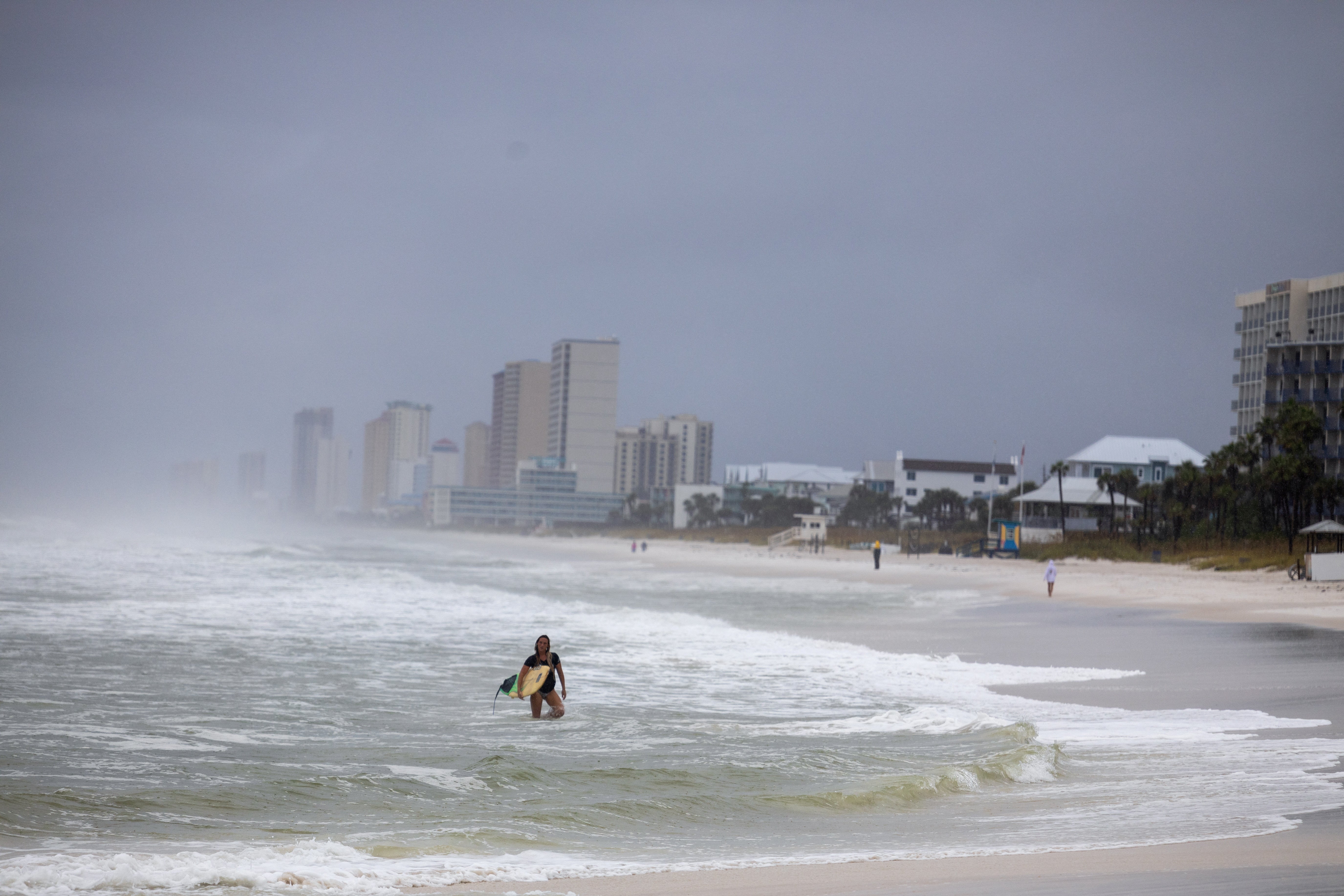 A person holds a surfboard on Panama City Beach before Helene’s landfall on Thursday