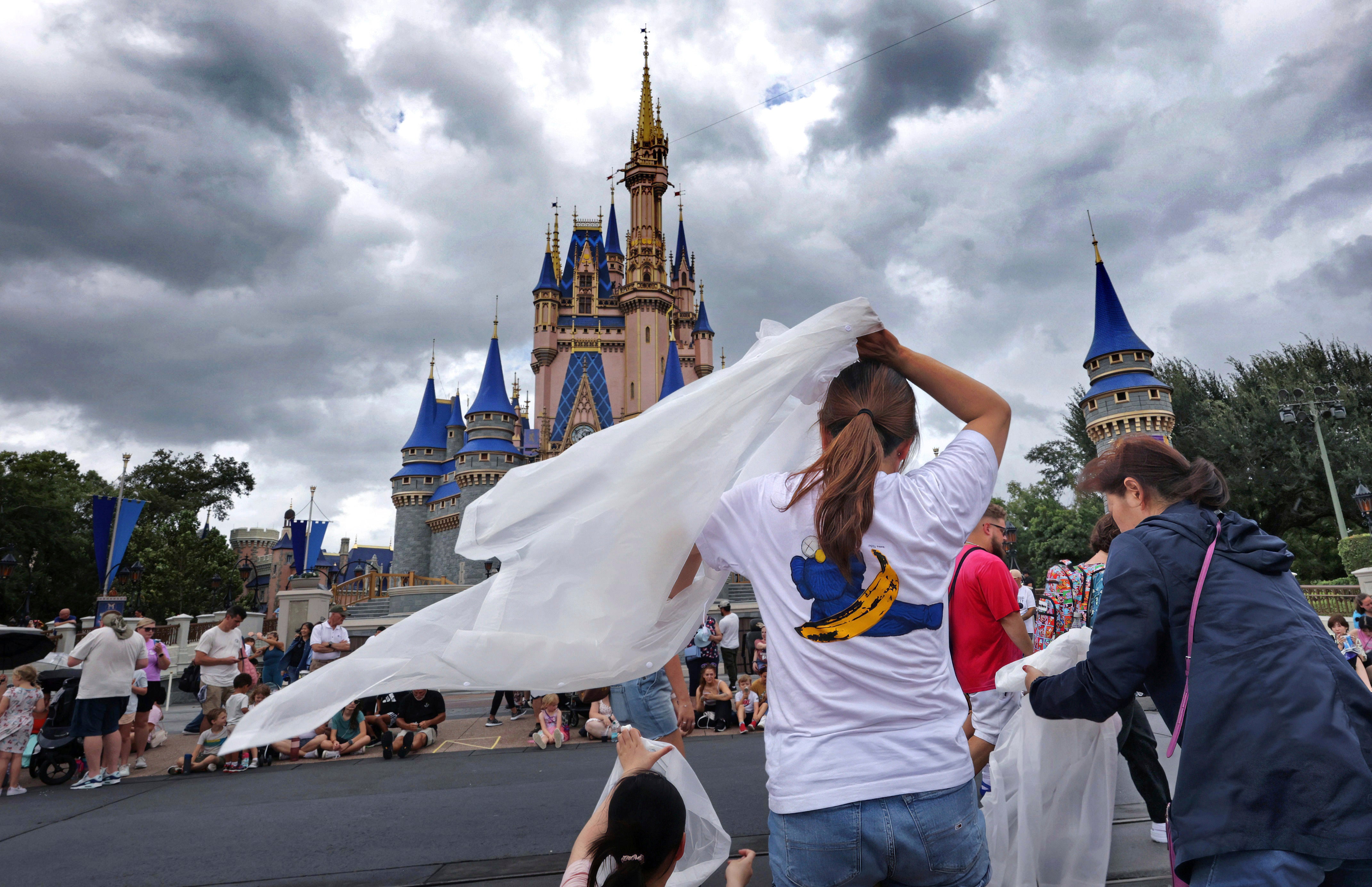 Walt Disney World guests break out ponchos at Cinderella Castle on Thursday, where some experiences were cancelled