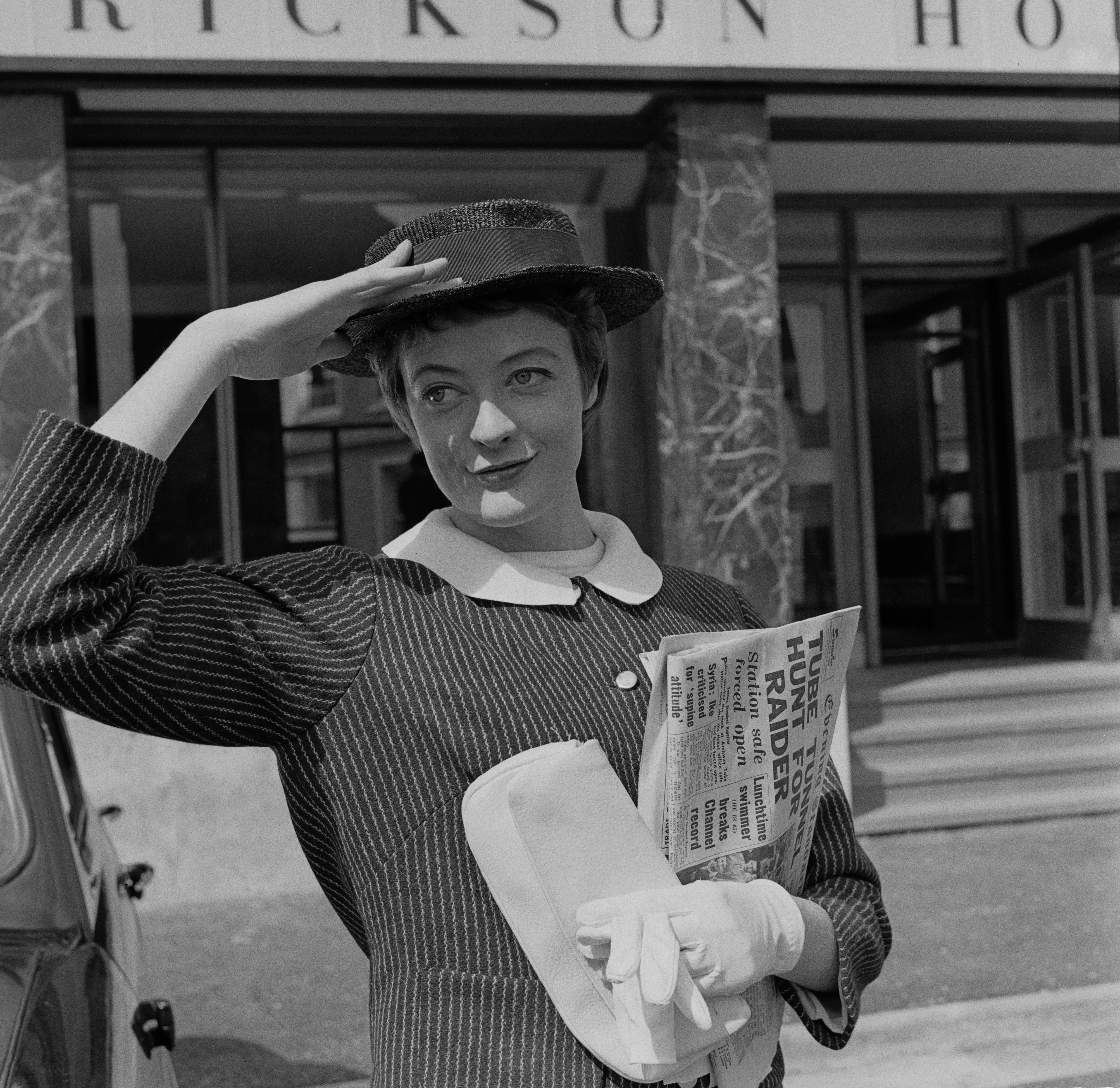 Dame Maggie poses with her hand on her hat in August 1957