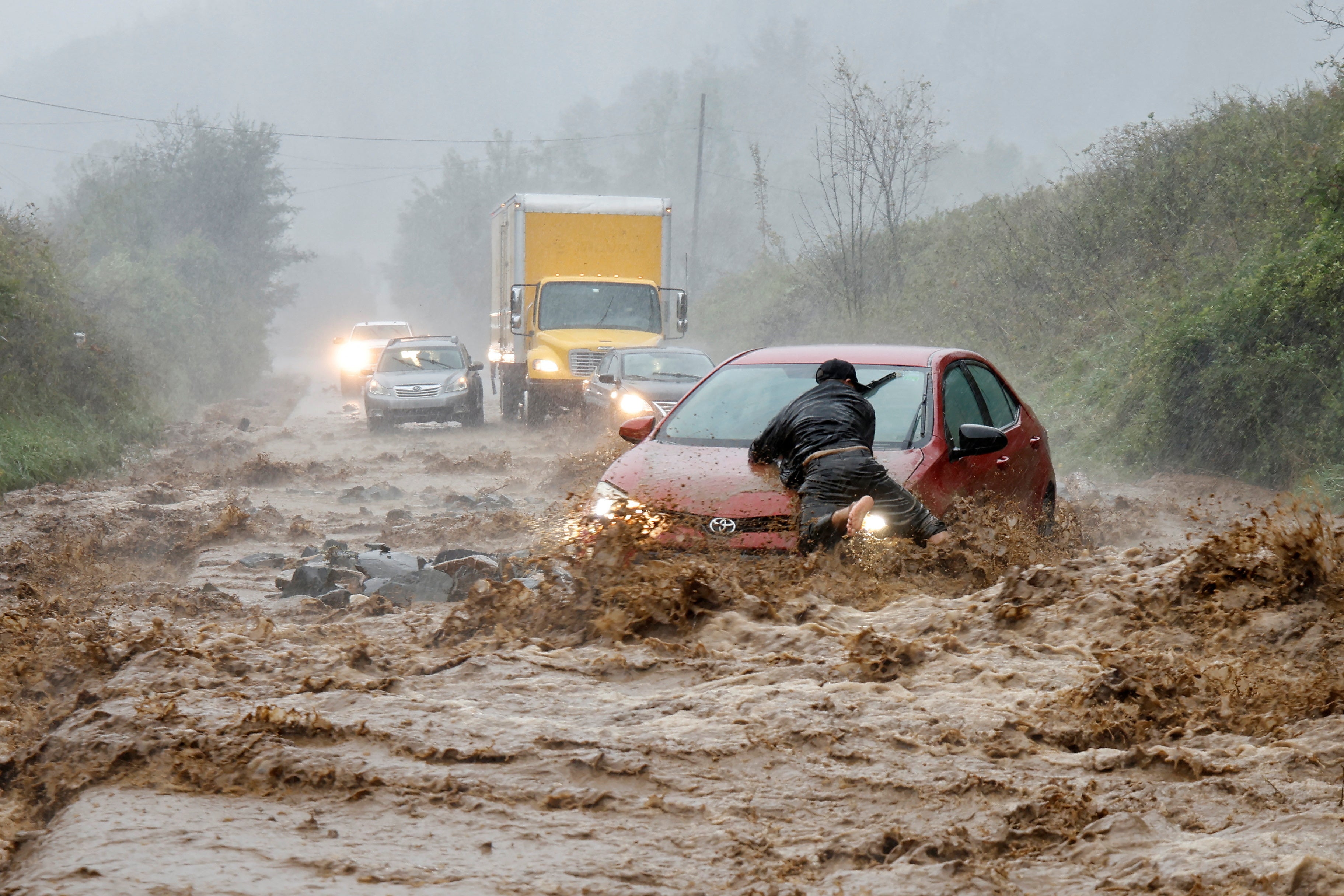 A local resident helps free a car that became stranded in a stretch of flooding road on Friday in Boone, North Carolina