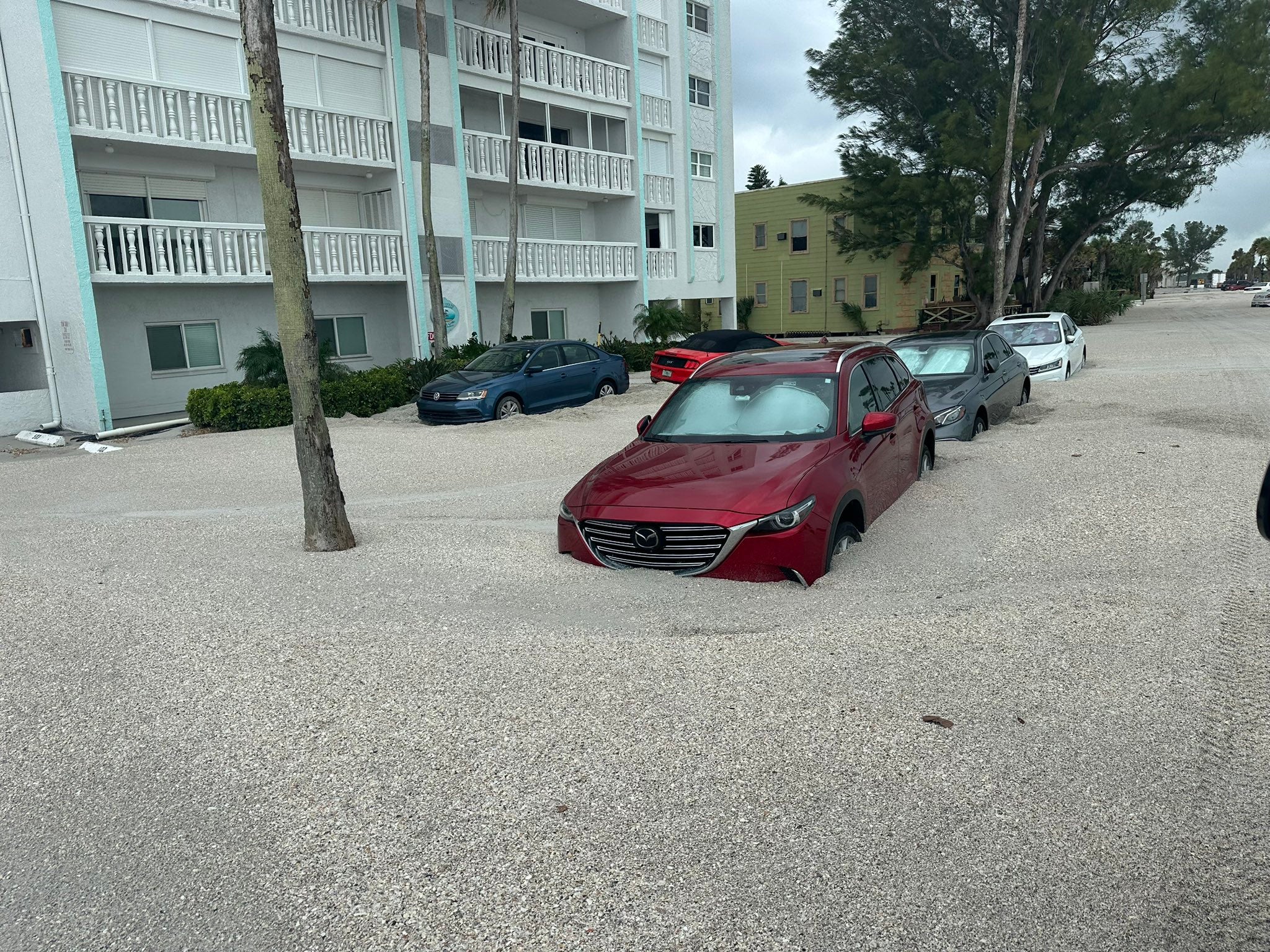 Parked cars are surrounded by sand picked up by Hurricane Helene in Pinellas County, Florida