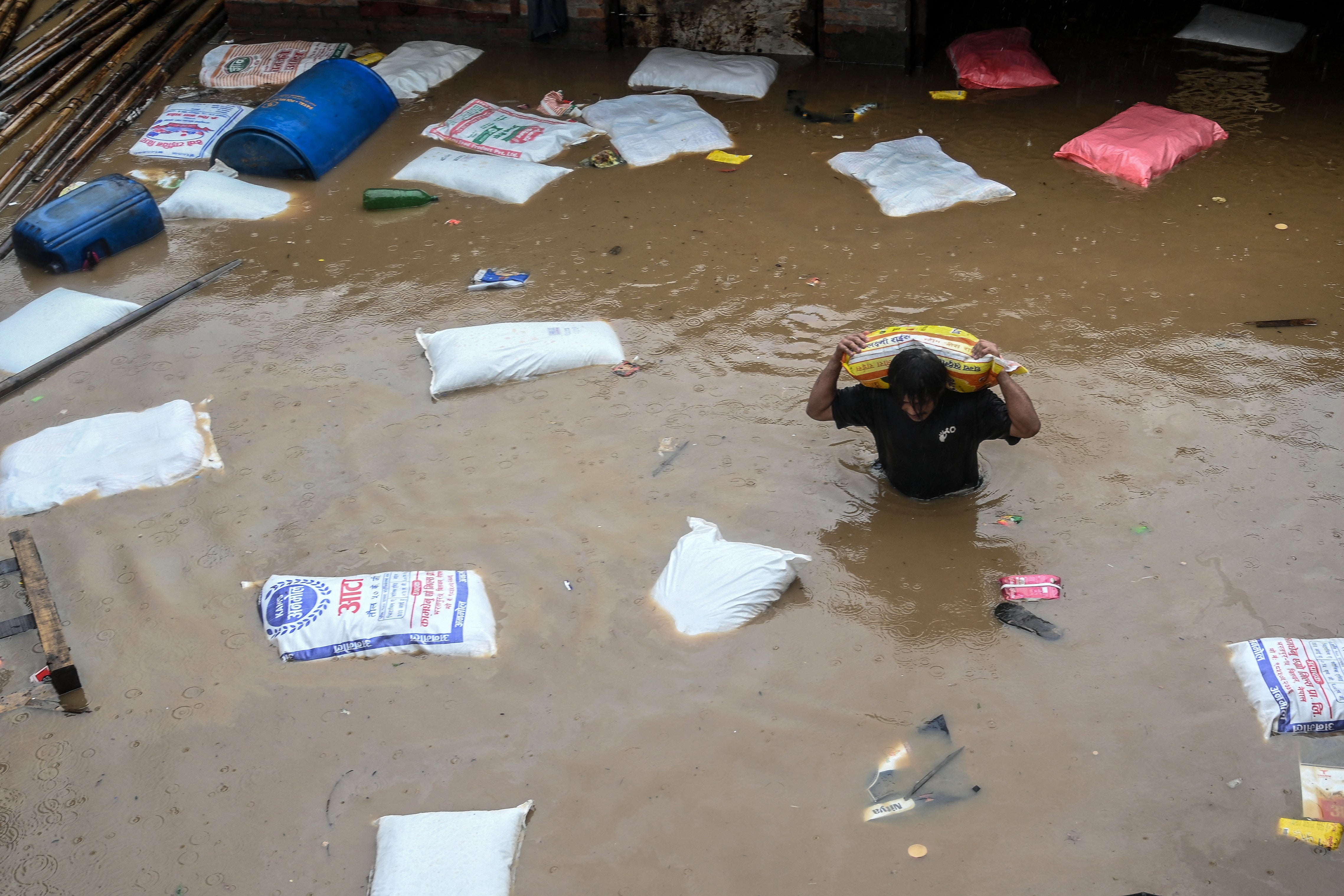 A man carrying a sack of flour wades through flood waters after the Bagmati River overflowed following heavy monsoon rains in Nepal