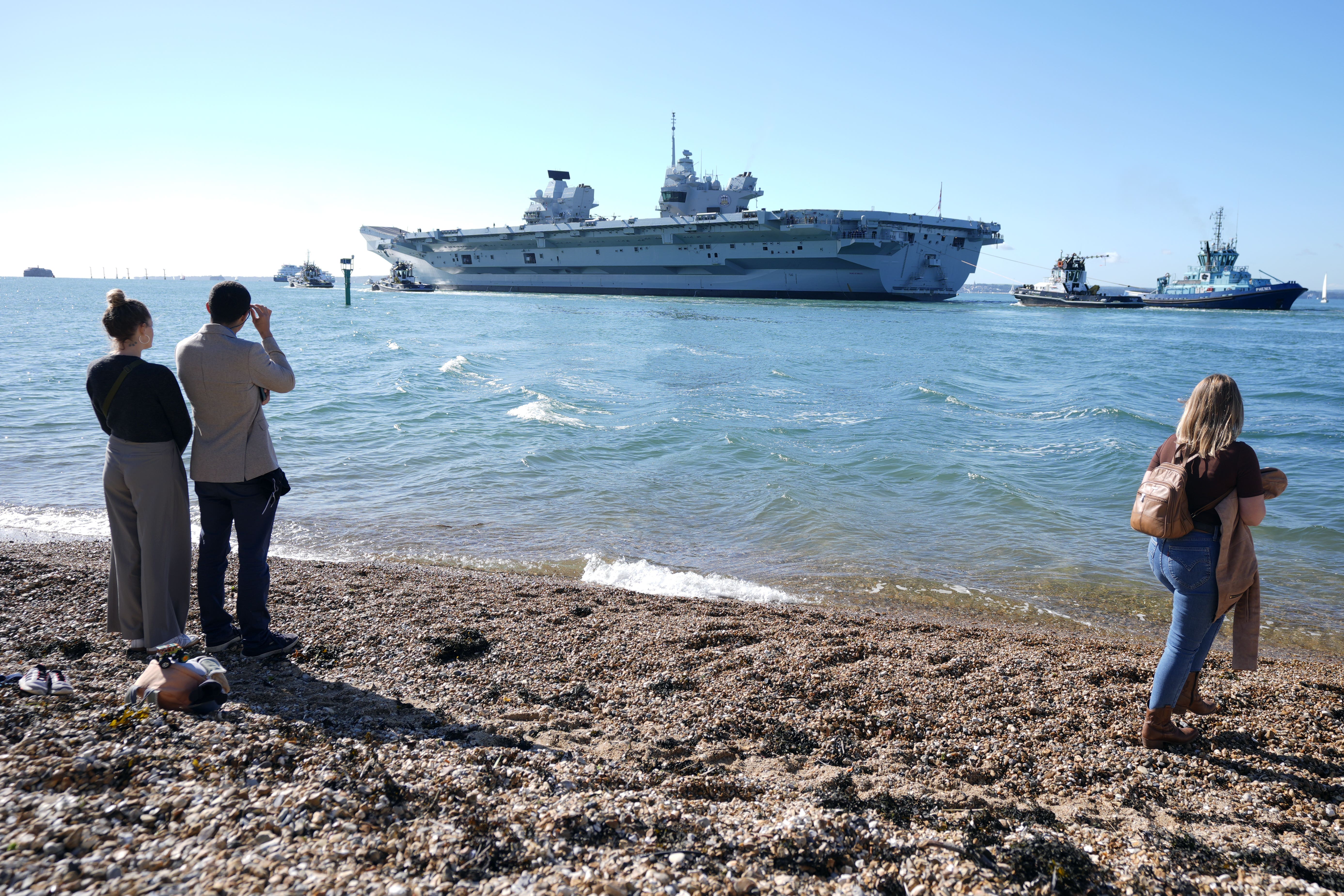 People look out from Hotwalls beach as the Royal Navy aircraft carrier HMS Prince of Wales sets sail (Andrew Matthews/PA)