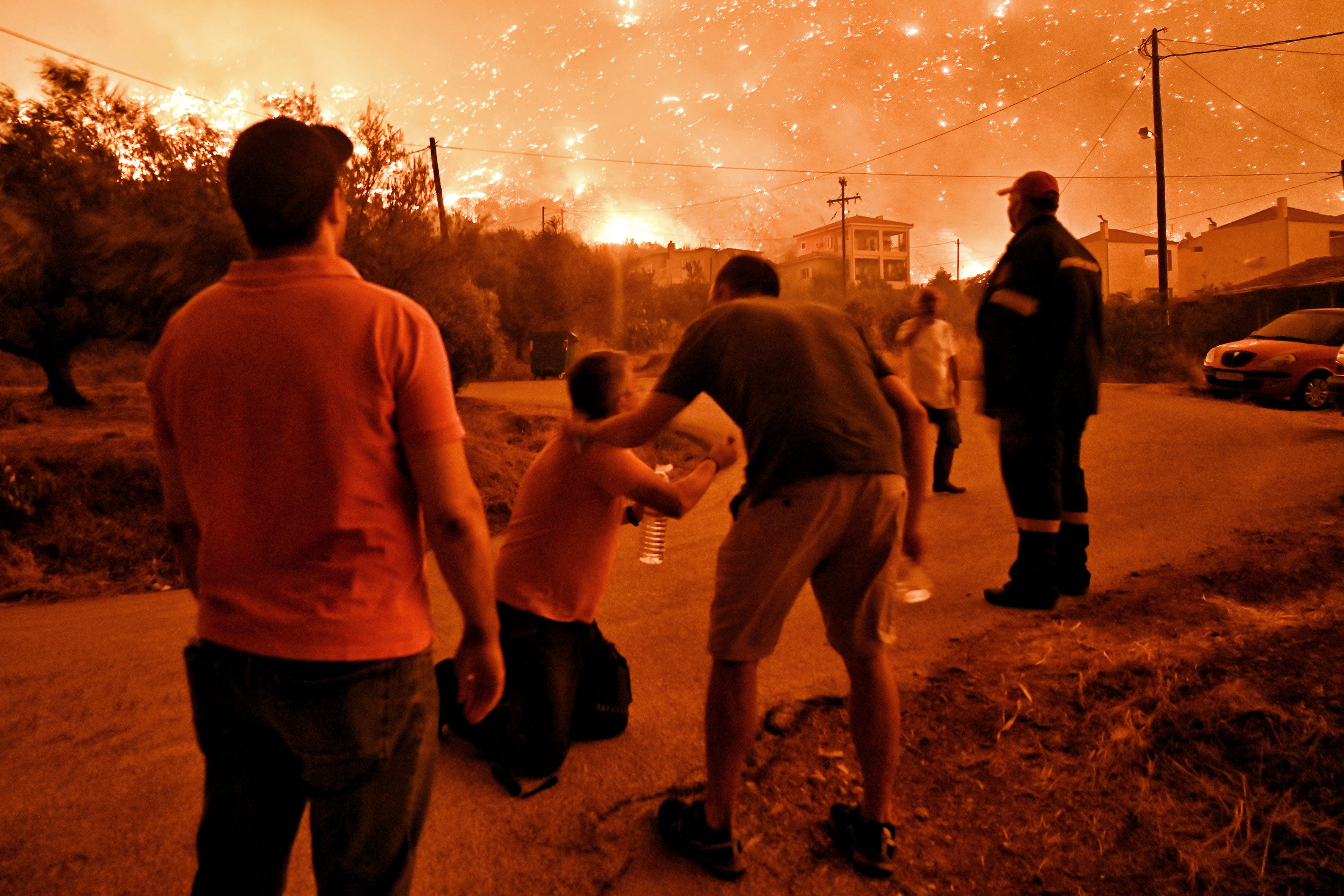 A resident reacts as a wildfire approaches the village of Ano Loutro as fanned by strong winds raged uncontrolled despite the attempts of hundreds of firefighters