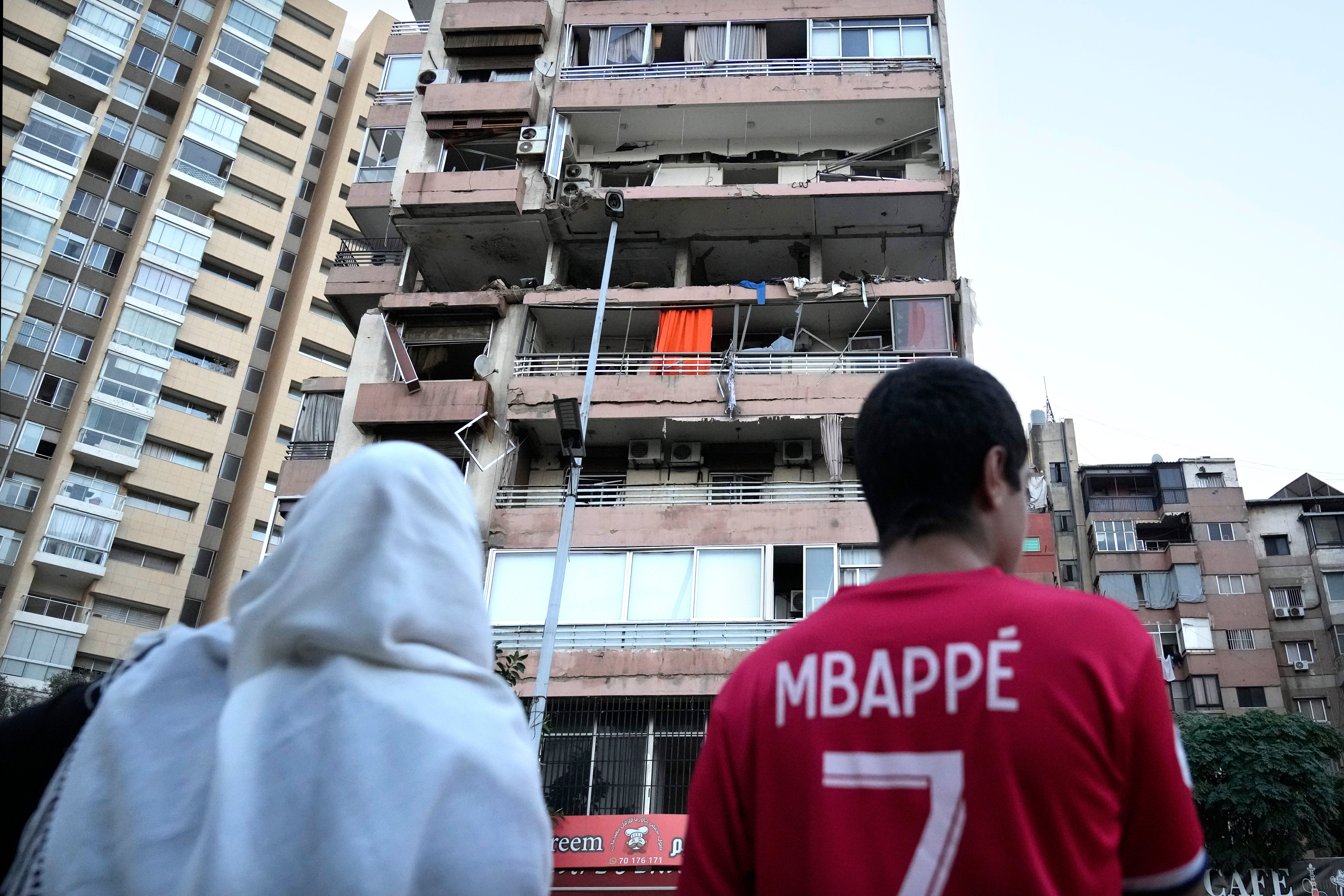 People look up at a damaged building that was hit by Israeli strike early Monday, Sept. 30, 2024, in Beirut, Lebanon