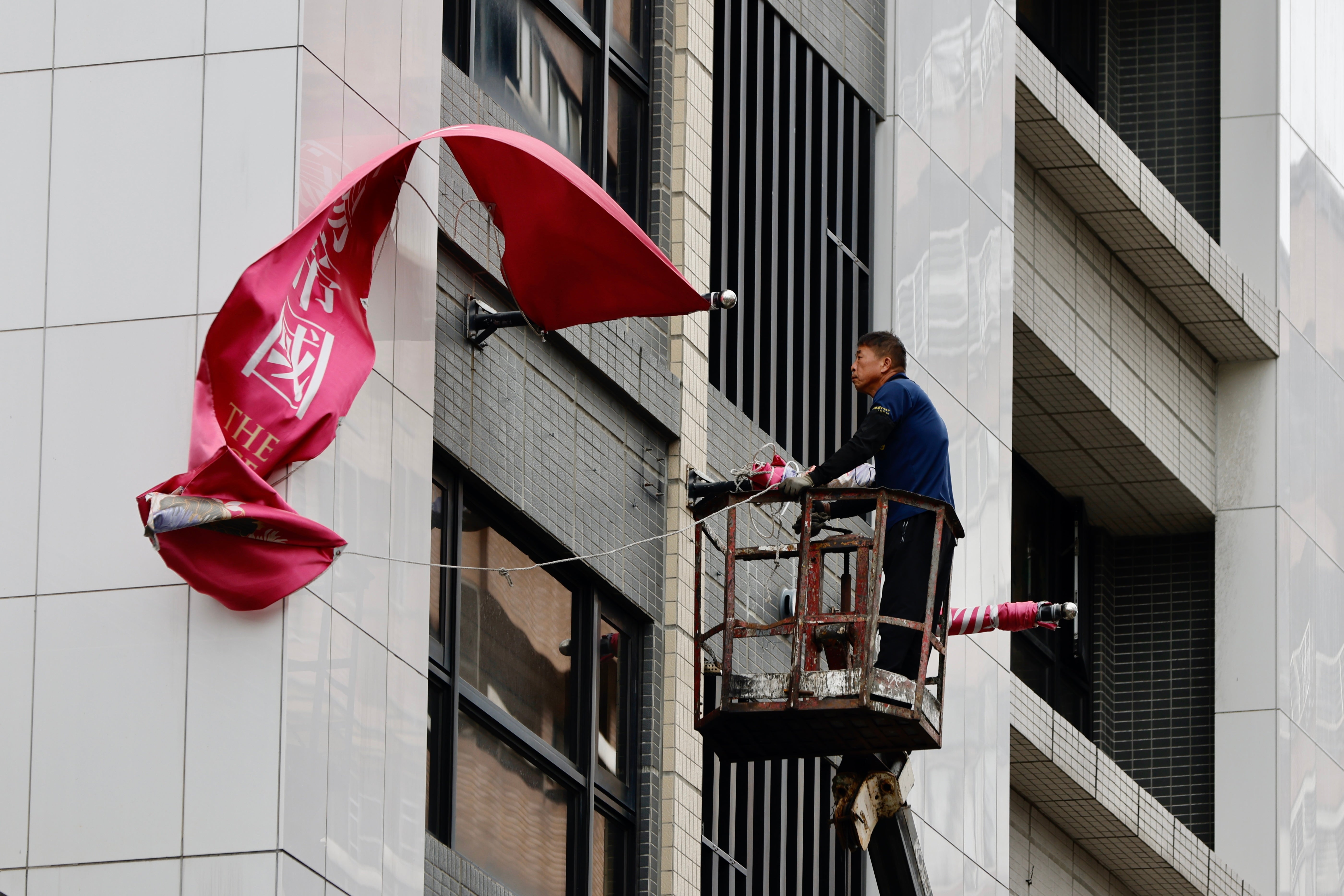 A Taiwanese worker folds advertising banners outside a building in anticipation for Typhoon Krathon in New Taipei City, Taiwan