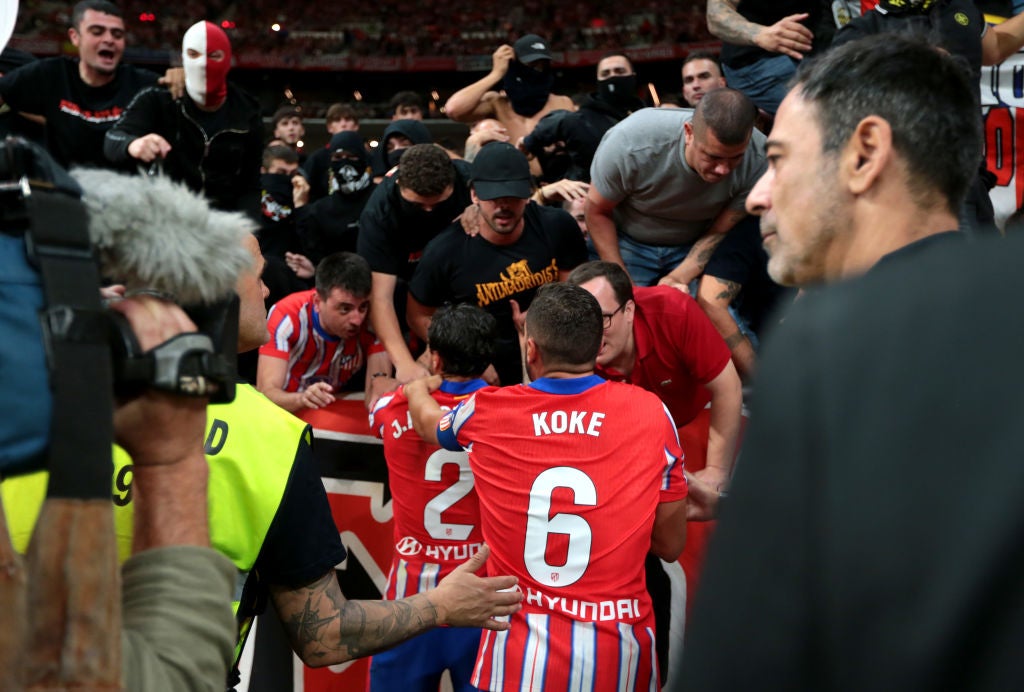 Jose Gimenez and Koke of Atletico Madrid plead with fans after objects are thrown at Thibaut Courtois