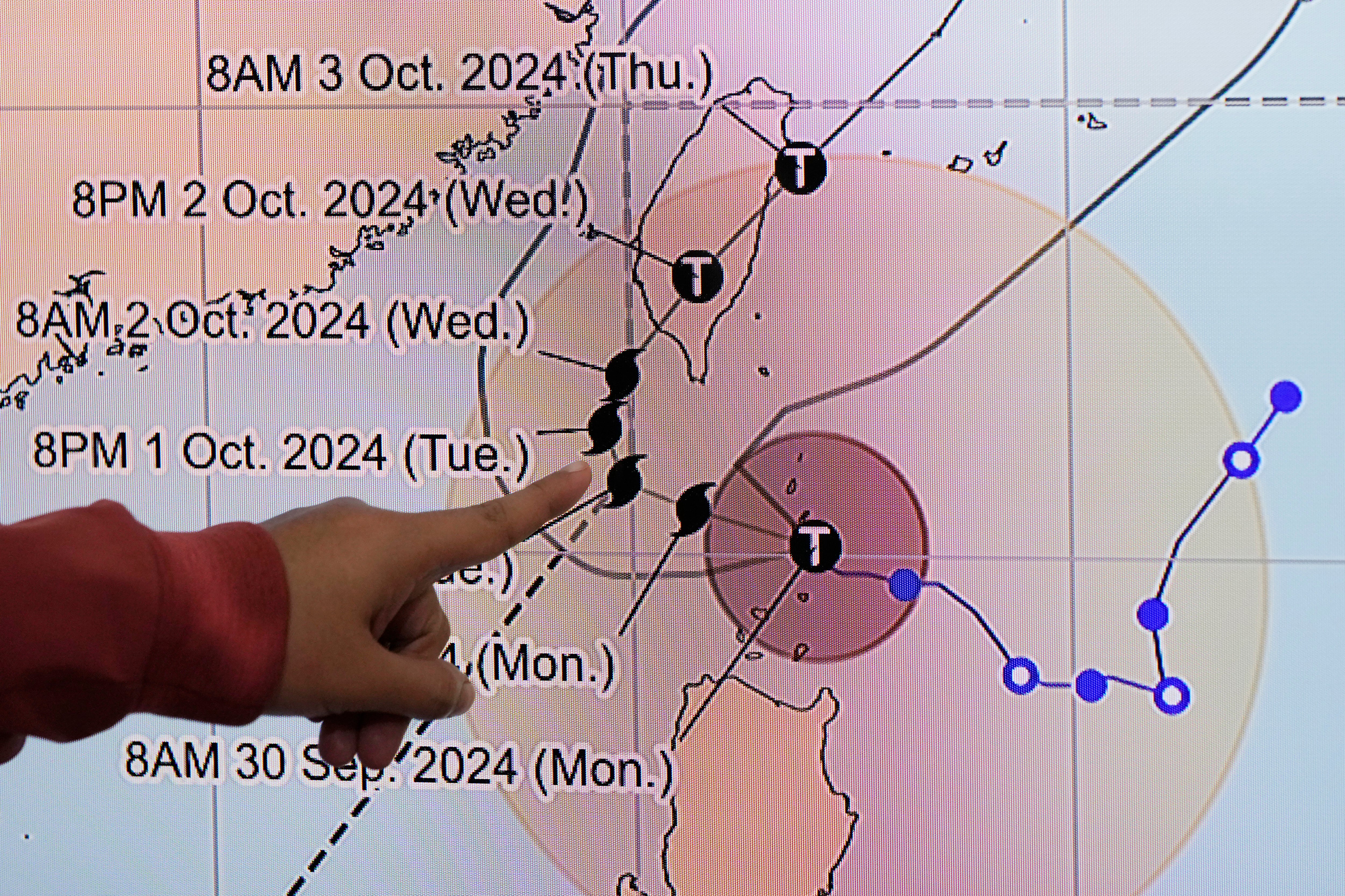 Philippine Atmospheric, Geophysical and Astronomical Services Administration weather specialist Veronica Torres points at the path of powerful Typhoon Krathon on Monday