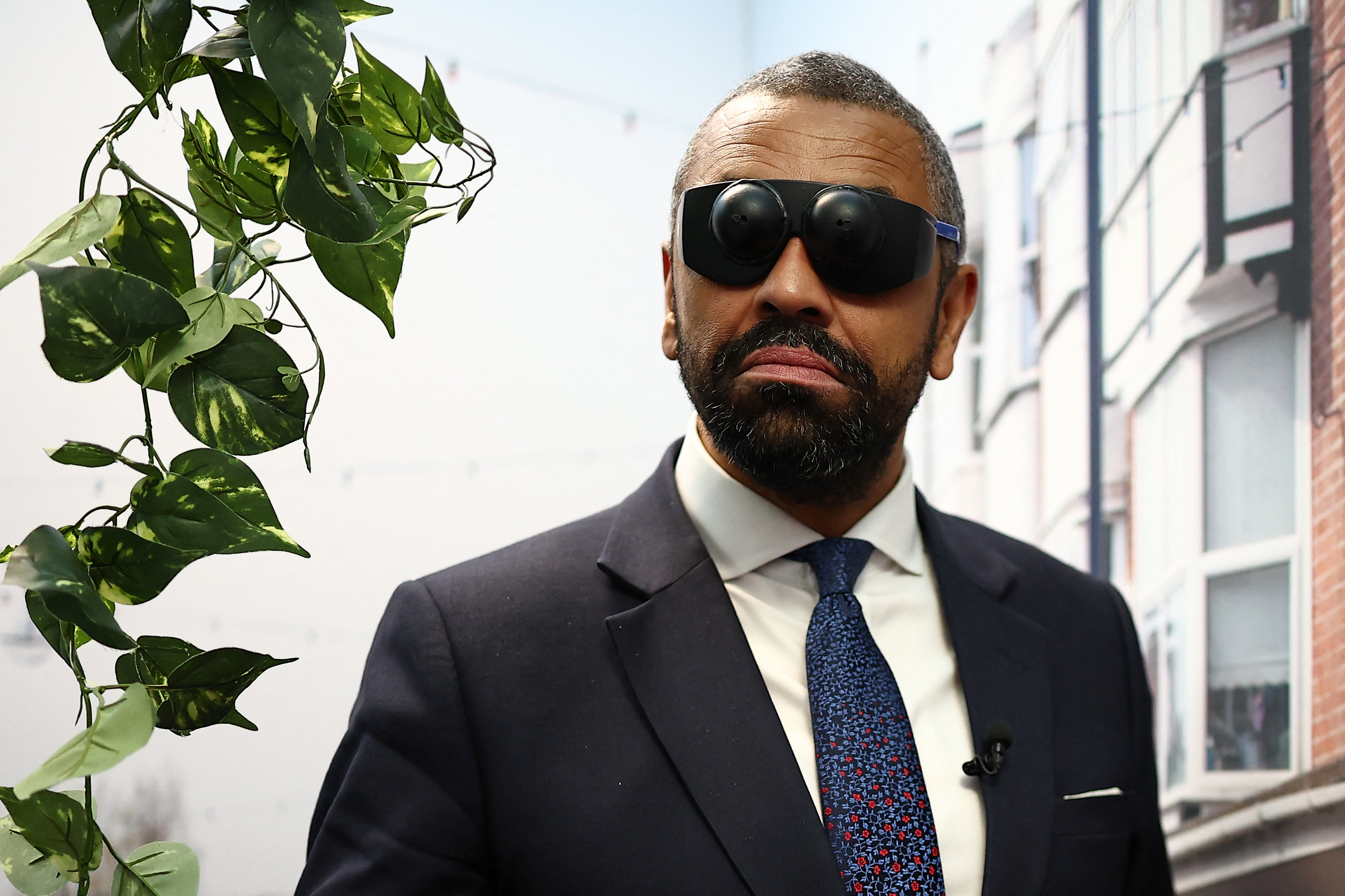 Shadow Home Secretary James Cleverly tries eyewear that replicates vision impairment, on a stand for a charity, on the second day of the annual Conservative Party Conference