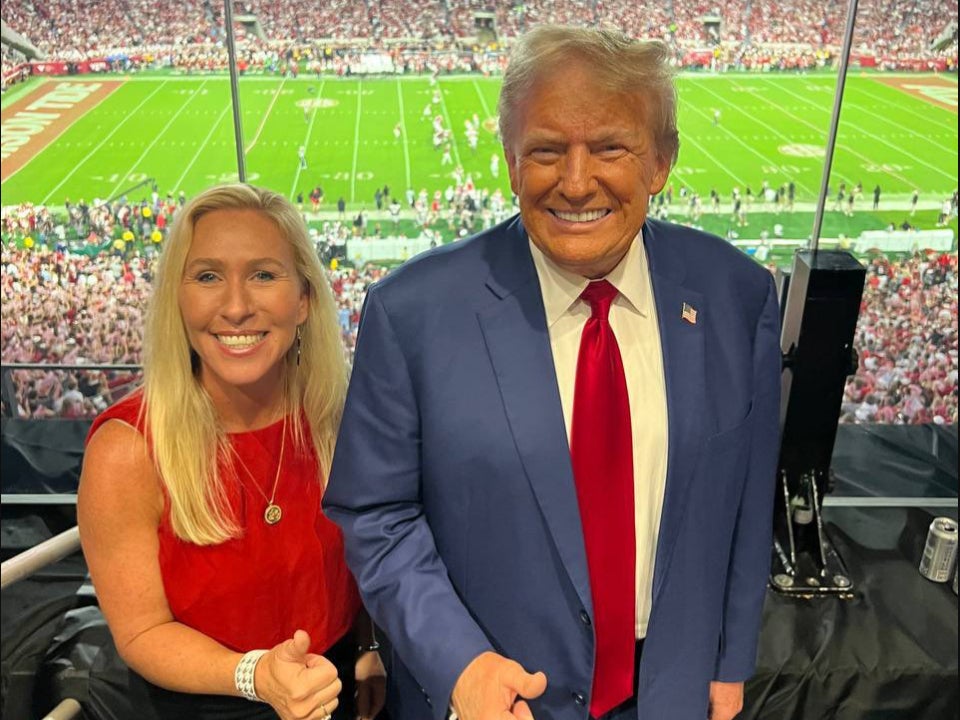 Marjorie Taylor Greene smiles beside Donald Trump at a Georgia v Alabama college football game. The congresswoman was slammed for enjoying a college football game while her state was devastated by Hurricane Helene