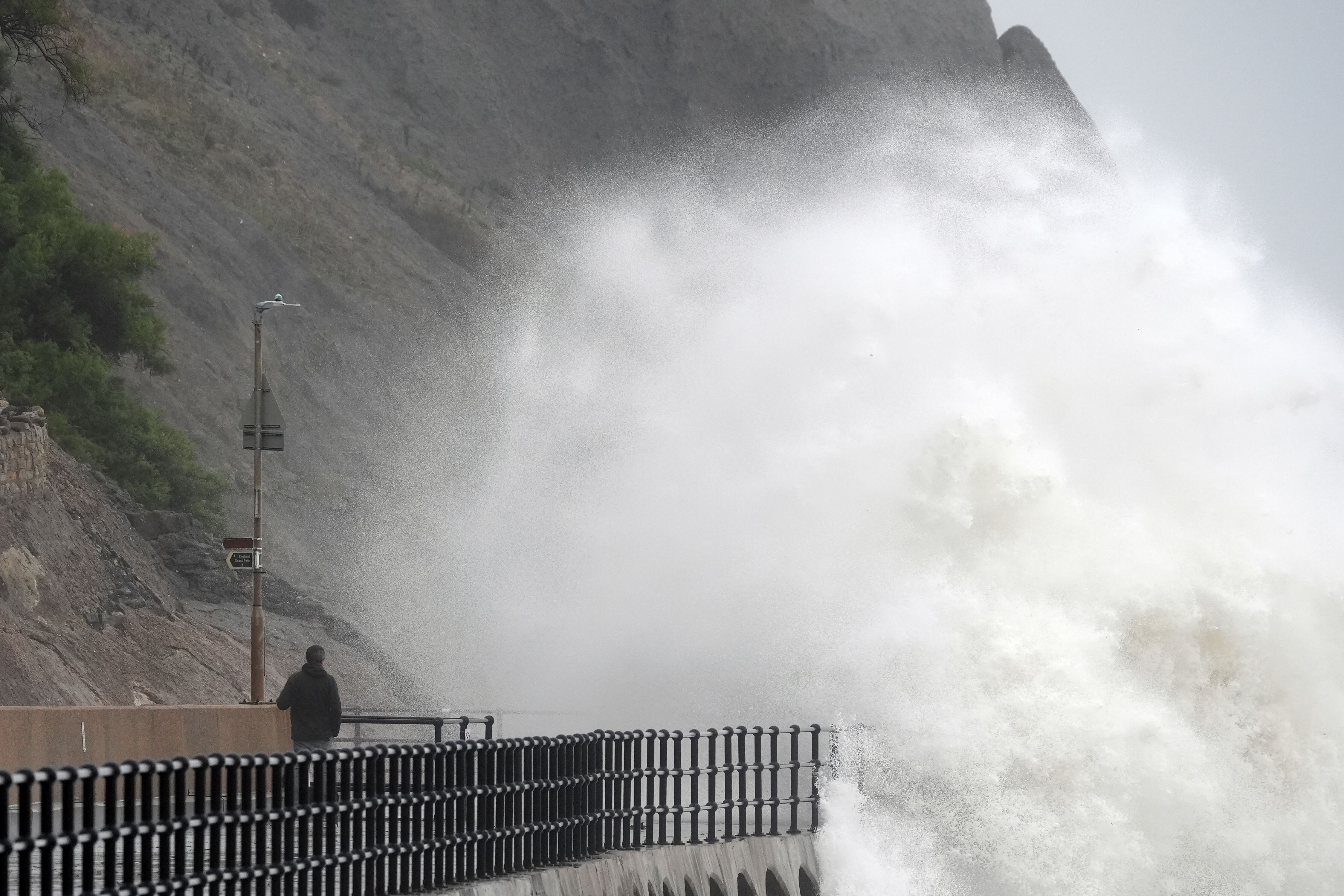 A person stands and watches as waves crash over the promenade in Folkestone (Gareth Fuller/PA)