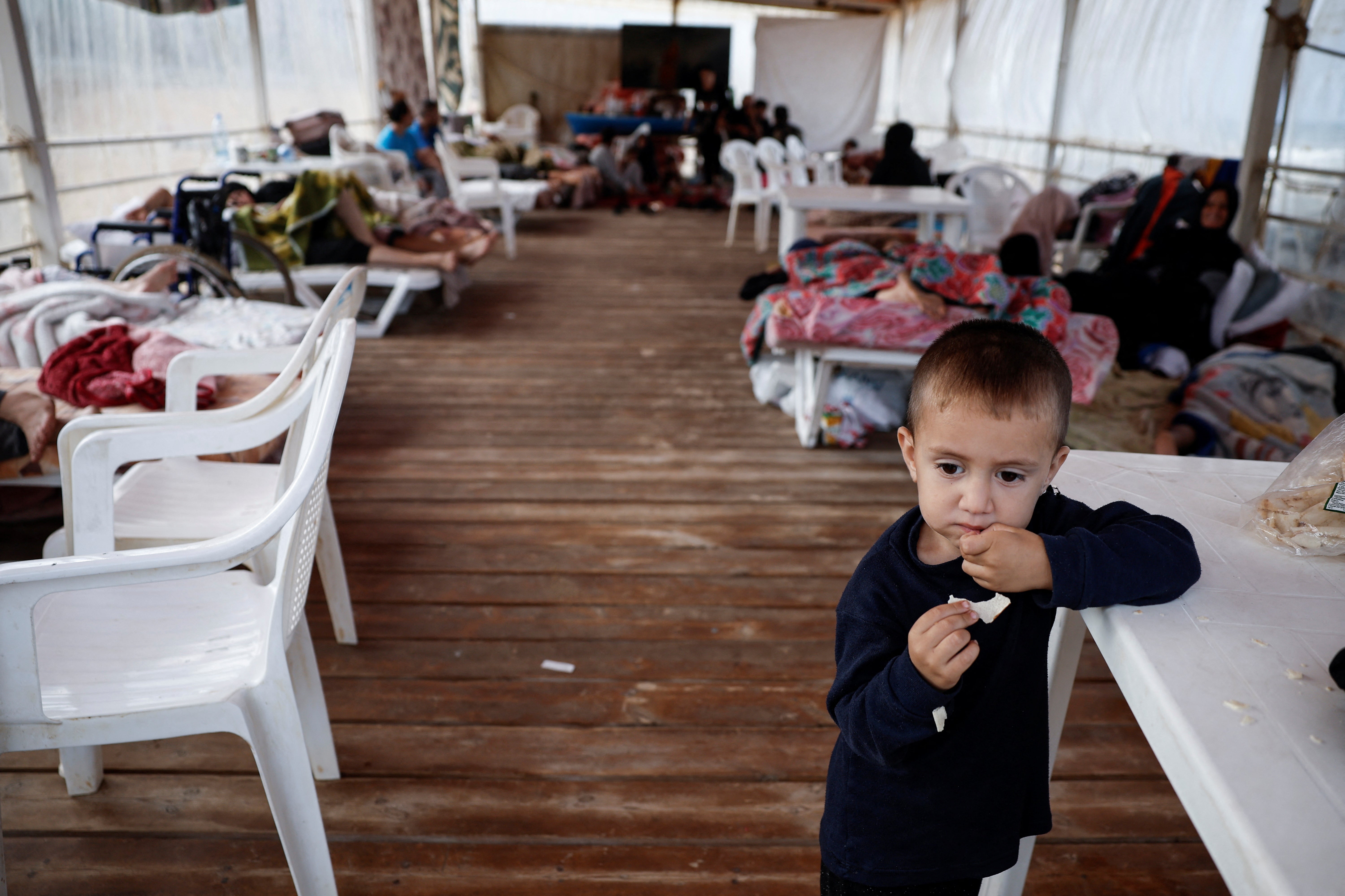 A displaced child eats at a makeshift encampment where scores of displaced people live, amid hostilities between Hezbollah and Israel, at a beach in Beirut, Lebanon