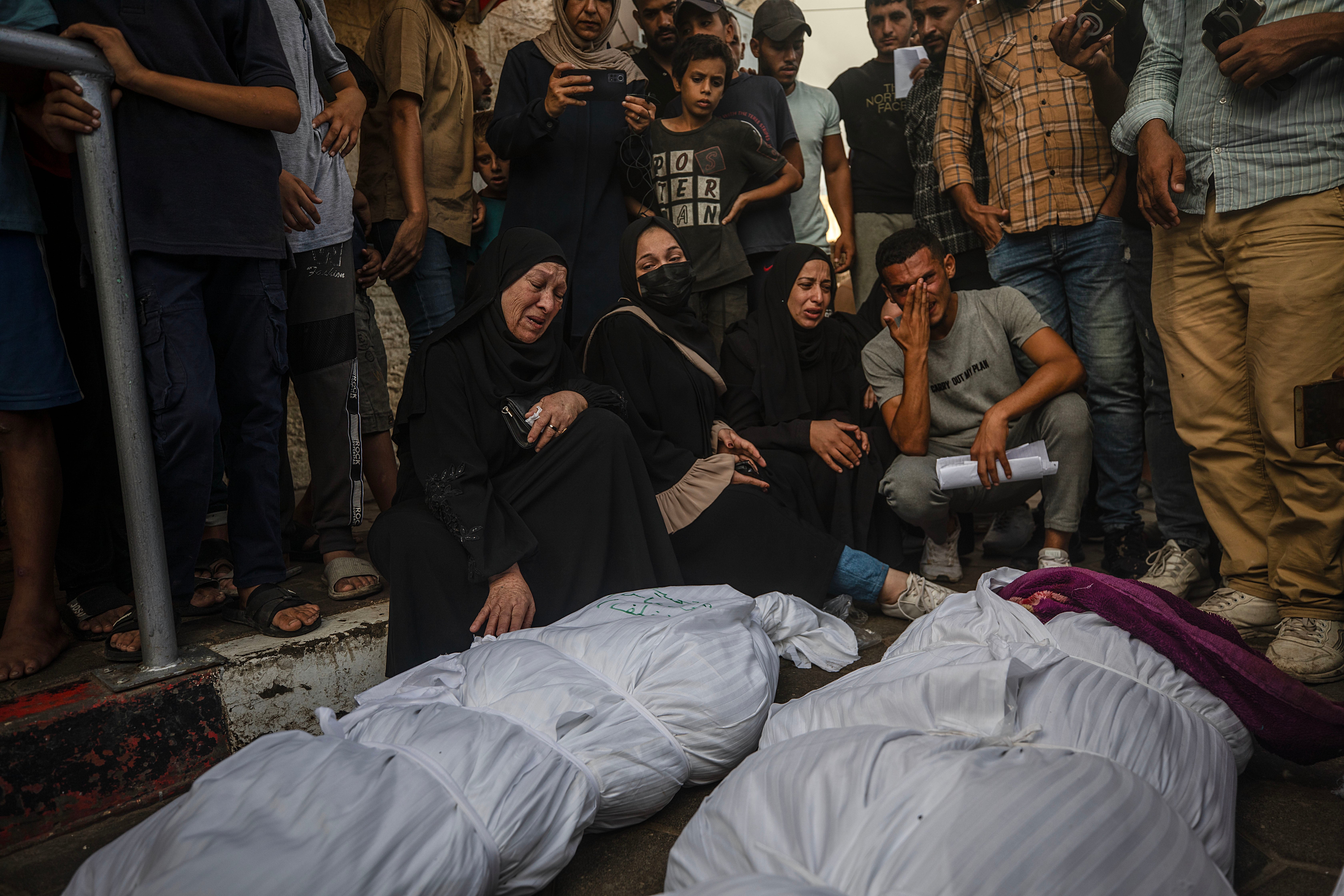 Relatives of late Al Dera family members mourn over their covered bodies during their funeral following an Israeli air strike in Al Nusairat refugee camp, central Gaza Strip