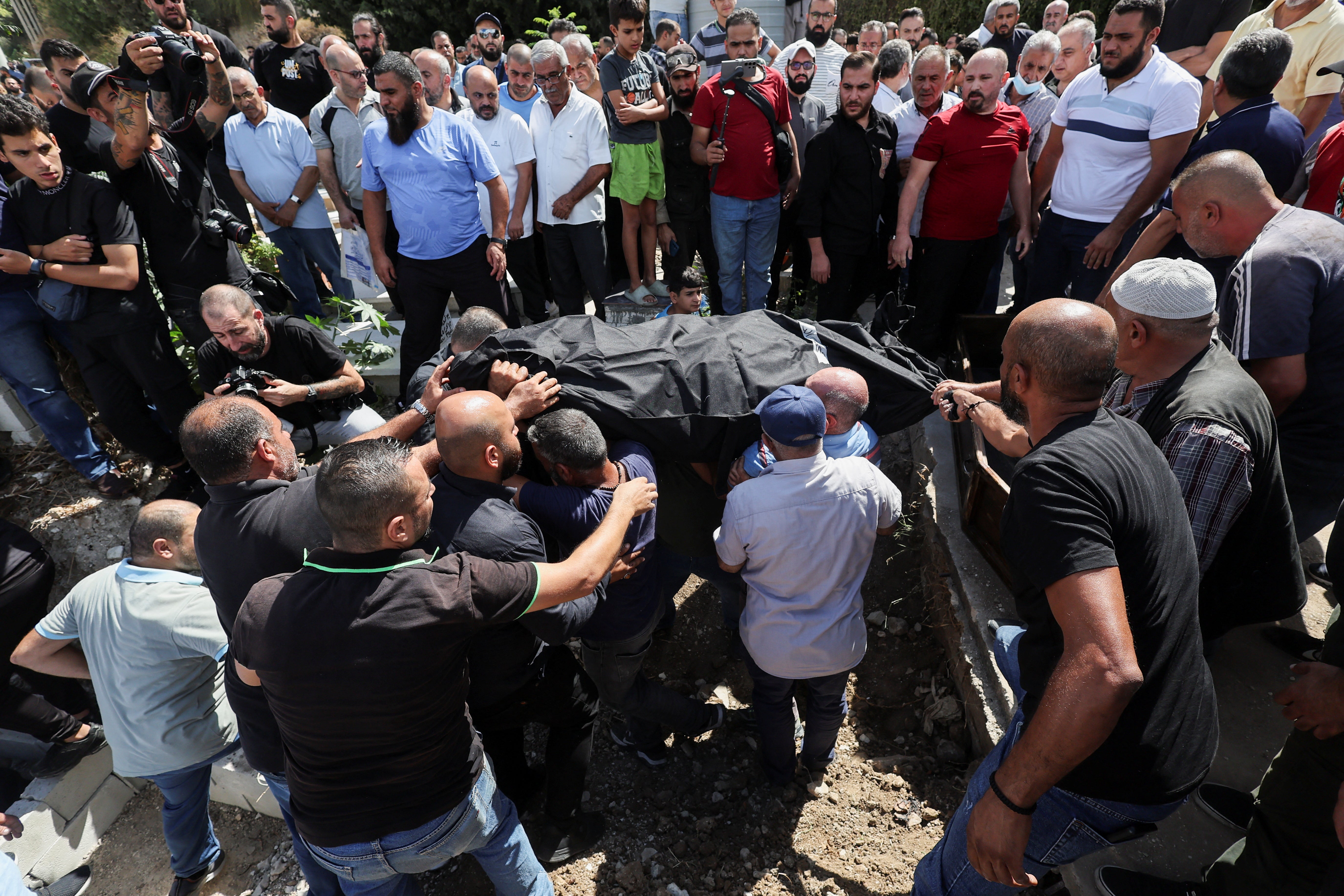 Mourners lower a body into a grave during the collective funeral held for people killed in an Israeli attack on Sunday in the city of Ain Deleb in southern Lebanon