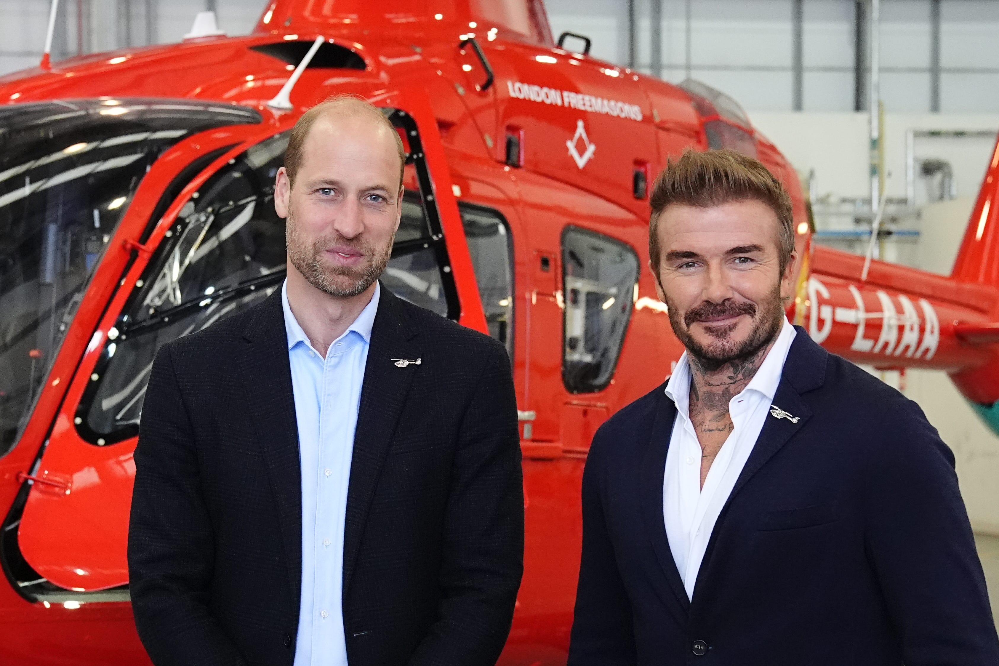 The Prince of Wales with David Beckham in front of one of the new London Air Ambulance Charity helicopters, during a visit to RAF Northolt (Aaron Chown/PA)