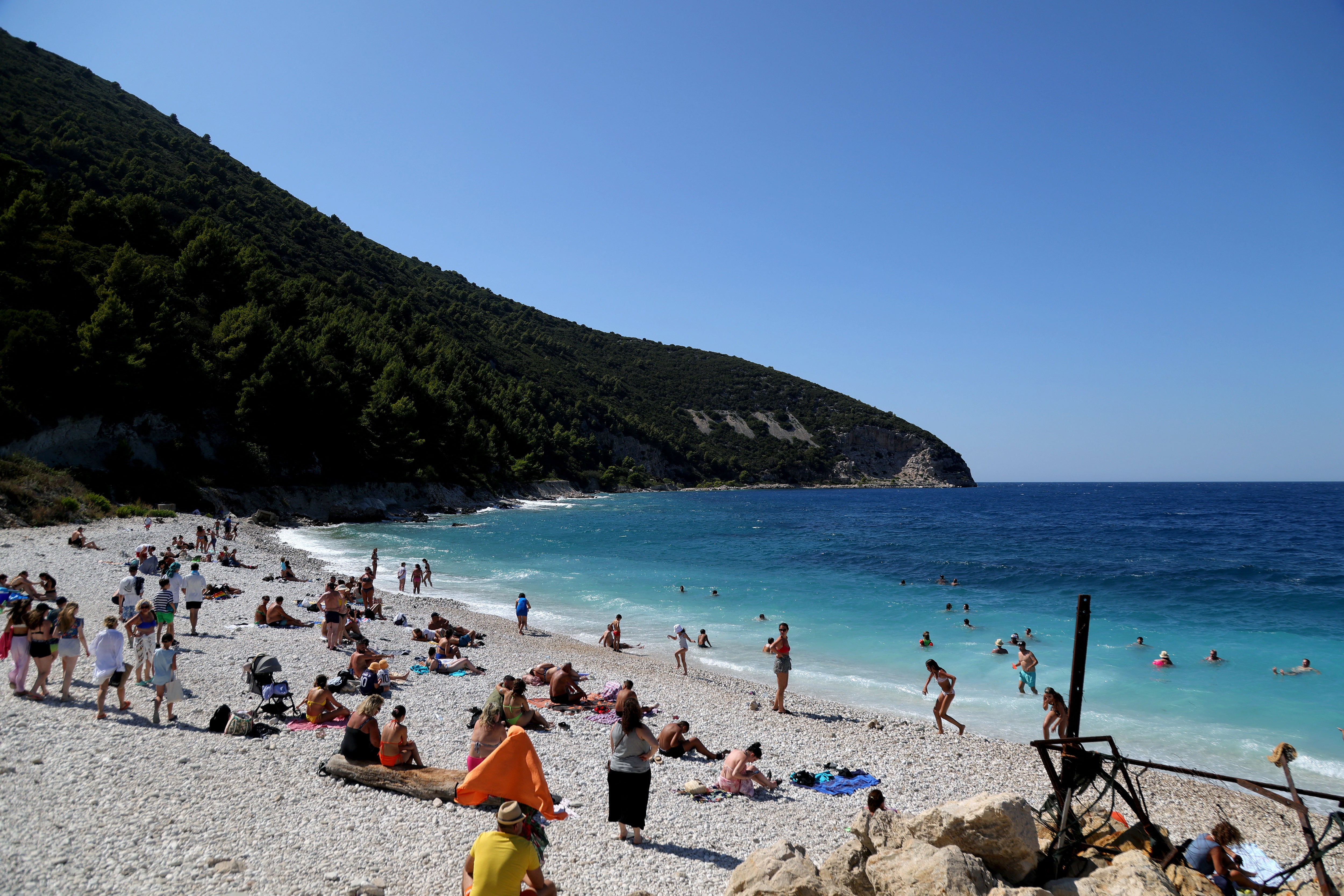 Tourists sunbath near the remains of a cold war bunker on a beach on the island of Sazan, near the Albanian city of Vlore