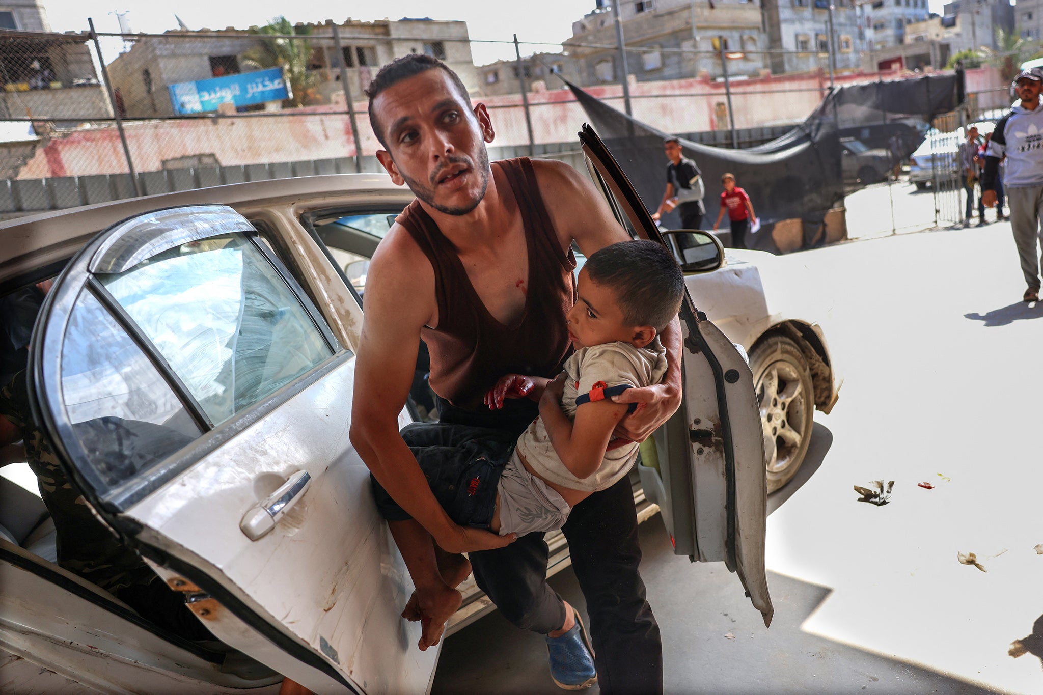 A Palestinian man rushes an injured child into a hospital after an Israeli bombardment