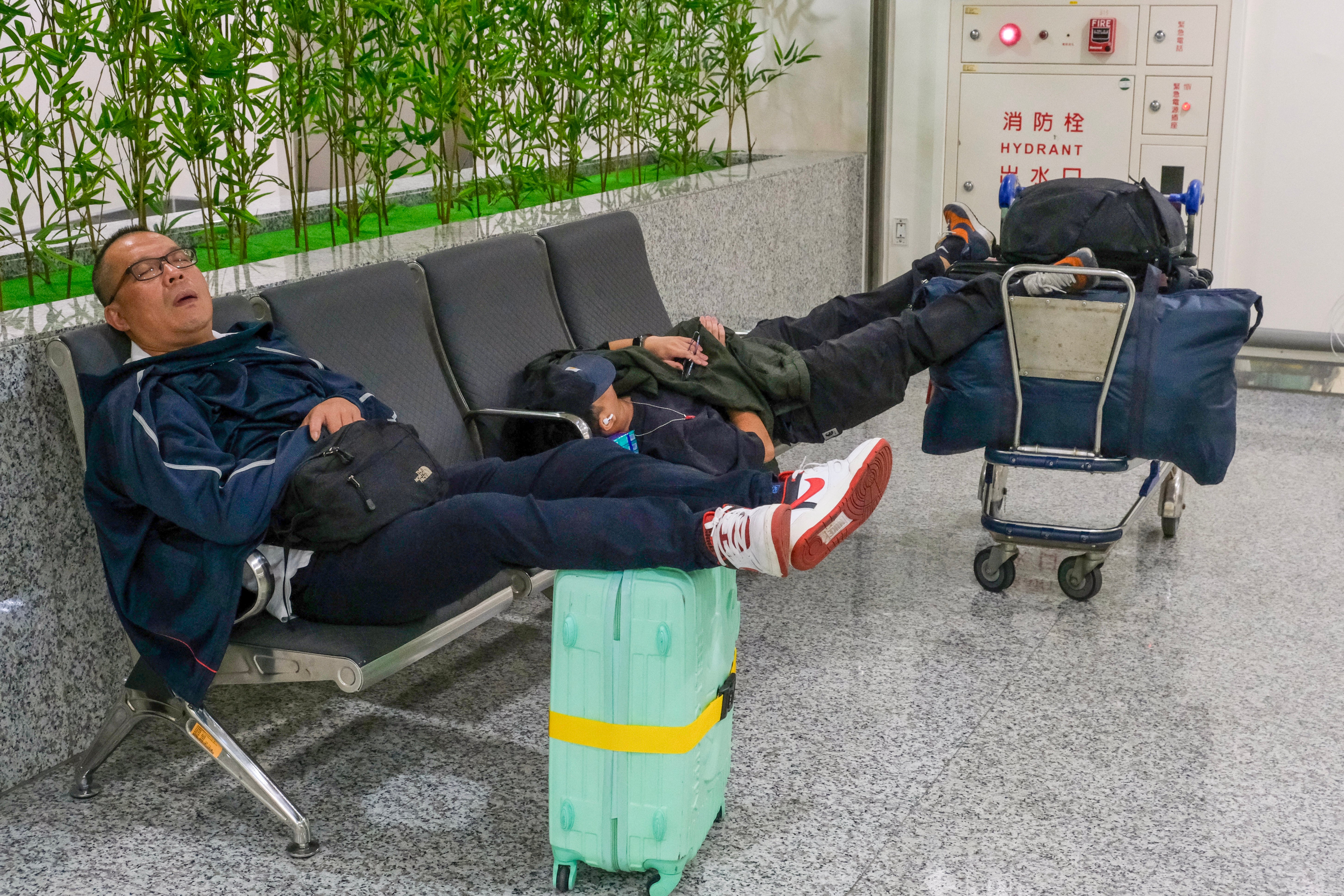 Passengers rest at the Taoyuan international airport amid flight cancellations