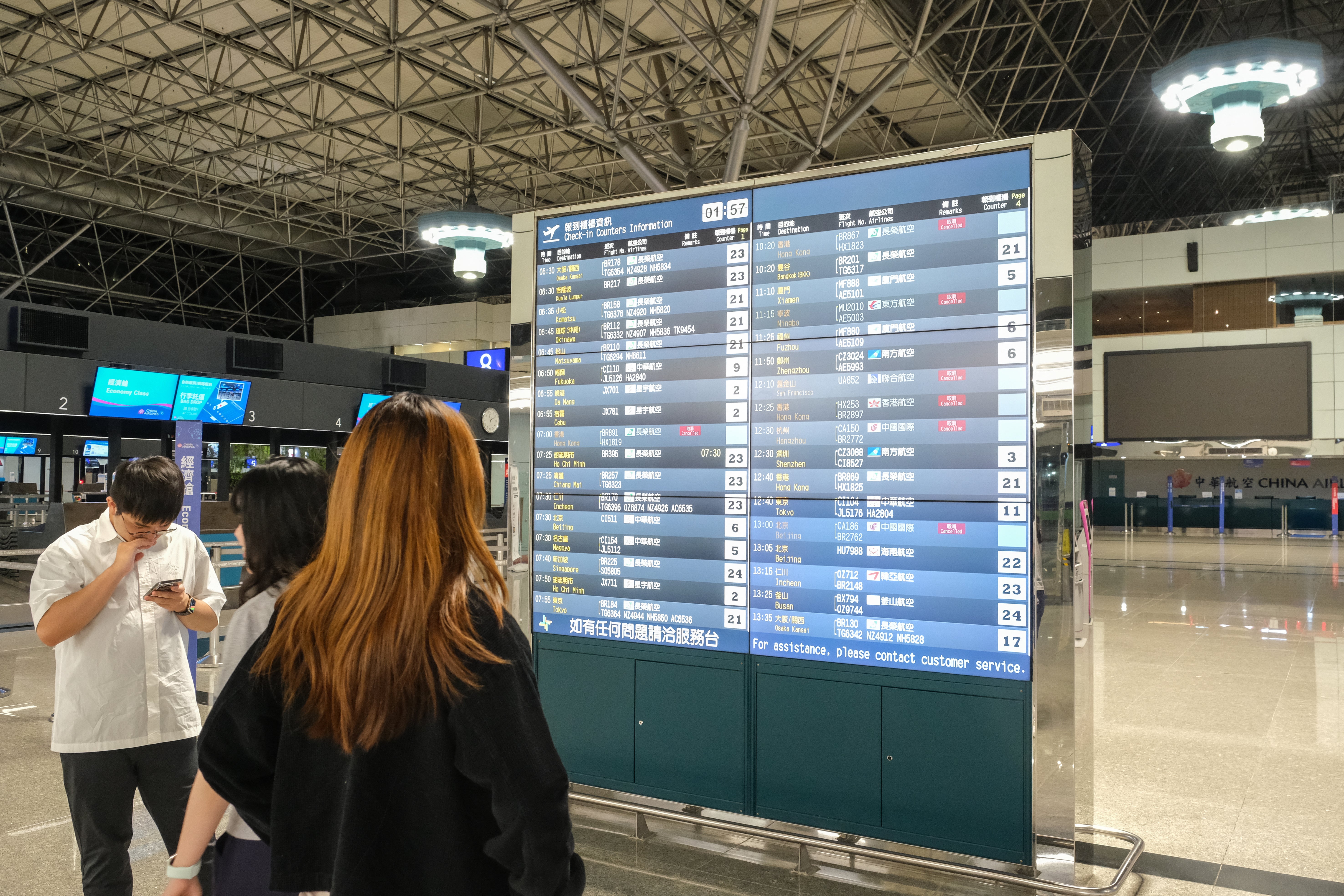 People look at an information board showing some cancelled flights at the Taoyuan international airport