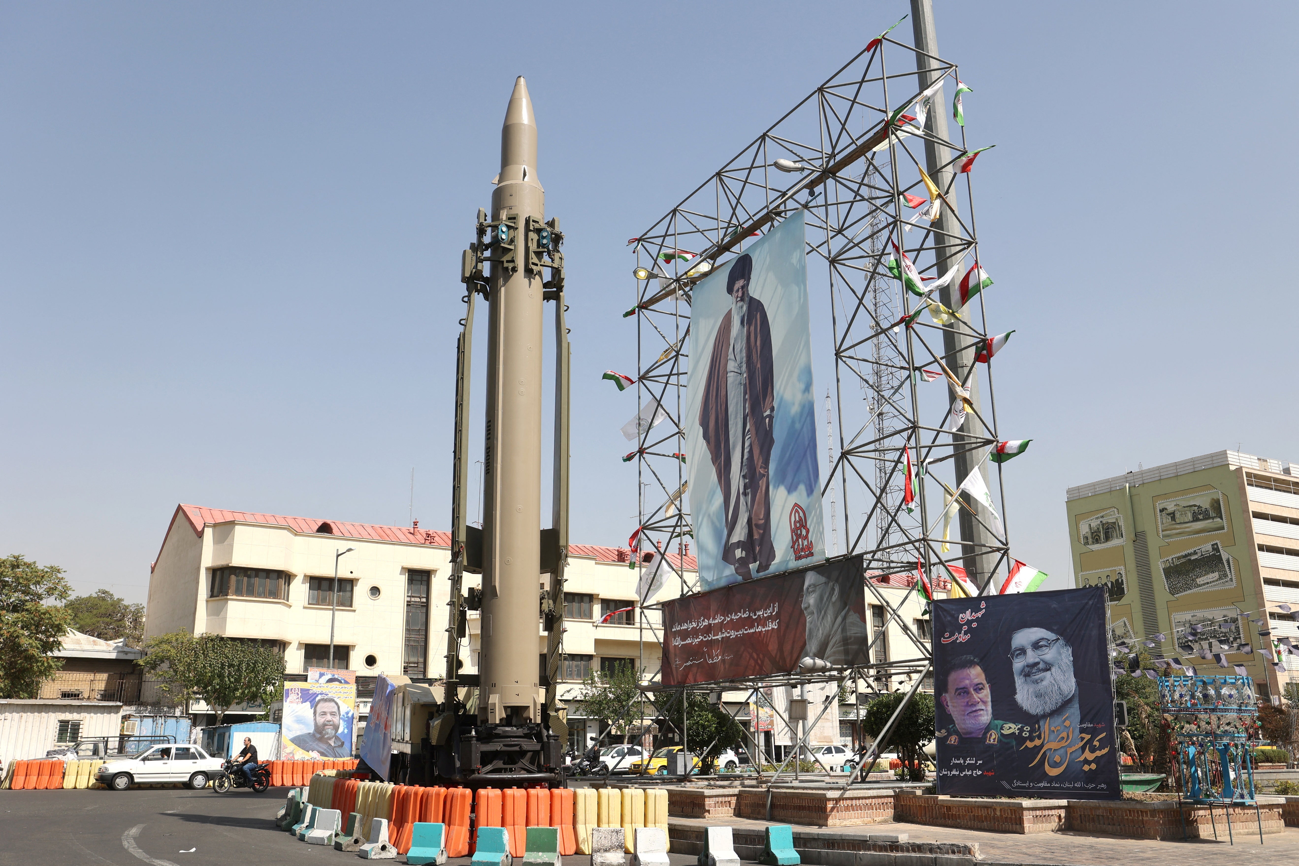 An Iranian missile system is displayed next to a banner with a picture of Iran’s Supreme Leader Ayatollah Ali Khamenei and the late Lebanon’s Hezbollah leader Hassan Nasrallah, in a street in Tehran, Iran