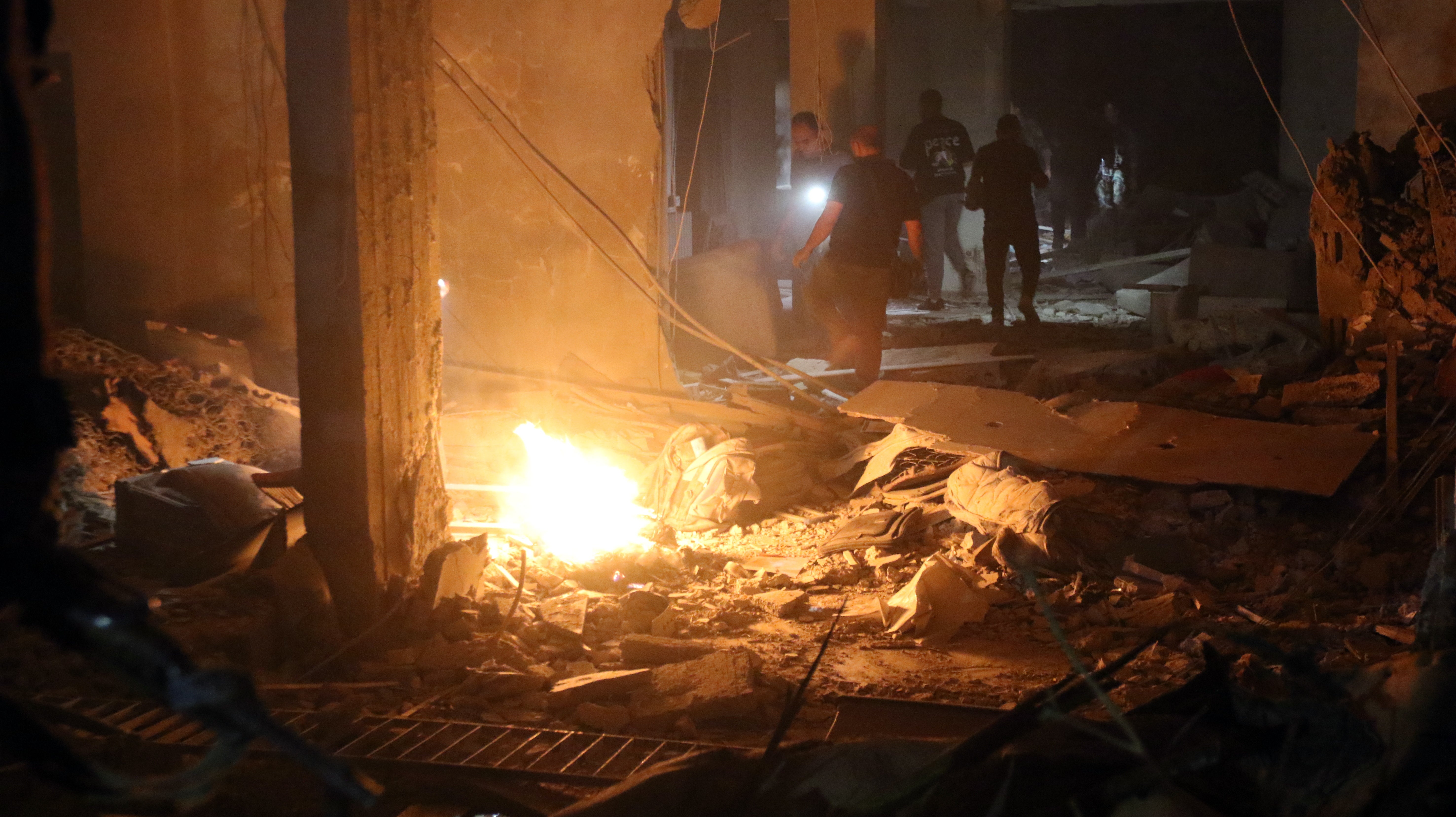 People inspect the site of a military strike in the Al-Mazzeh neighborhood in Damascus, Syria