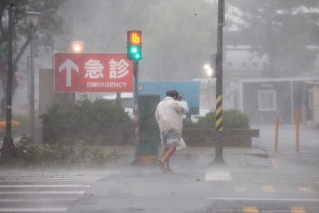 <p> A person crosses the street through strong winds and heavy rain brought on by Typhoon Krathon in Kaohsiung city, Taiwan</p>