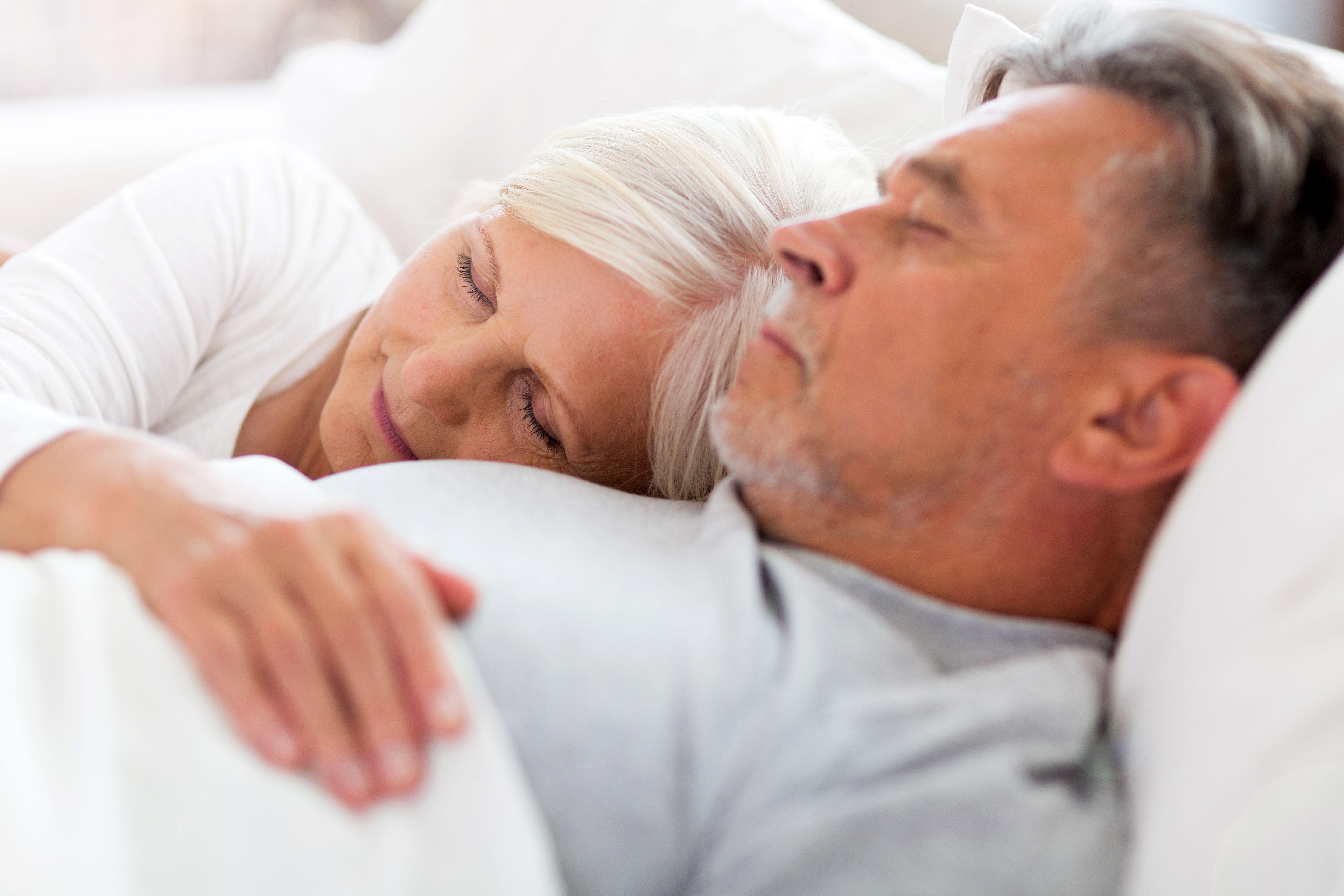 Senior man and woman in bed together struggling to sleep