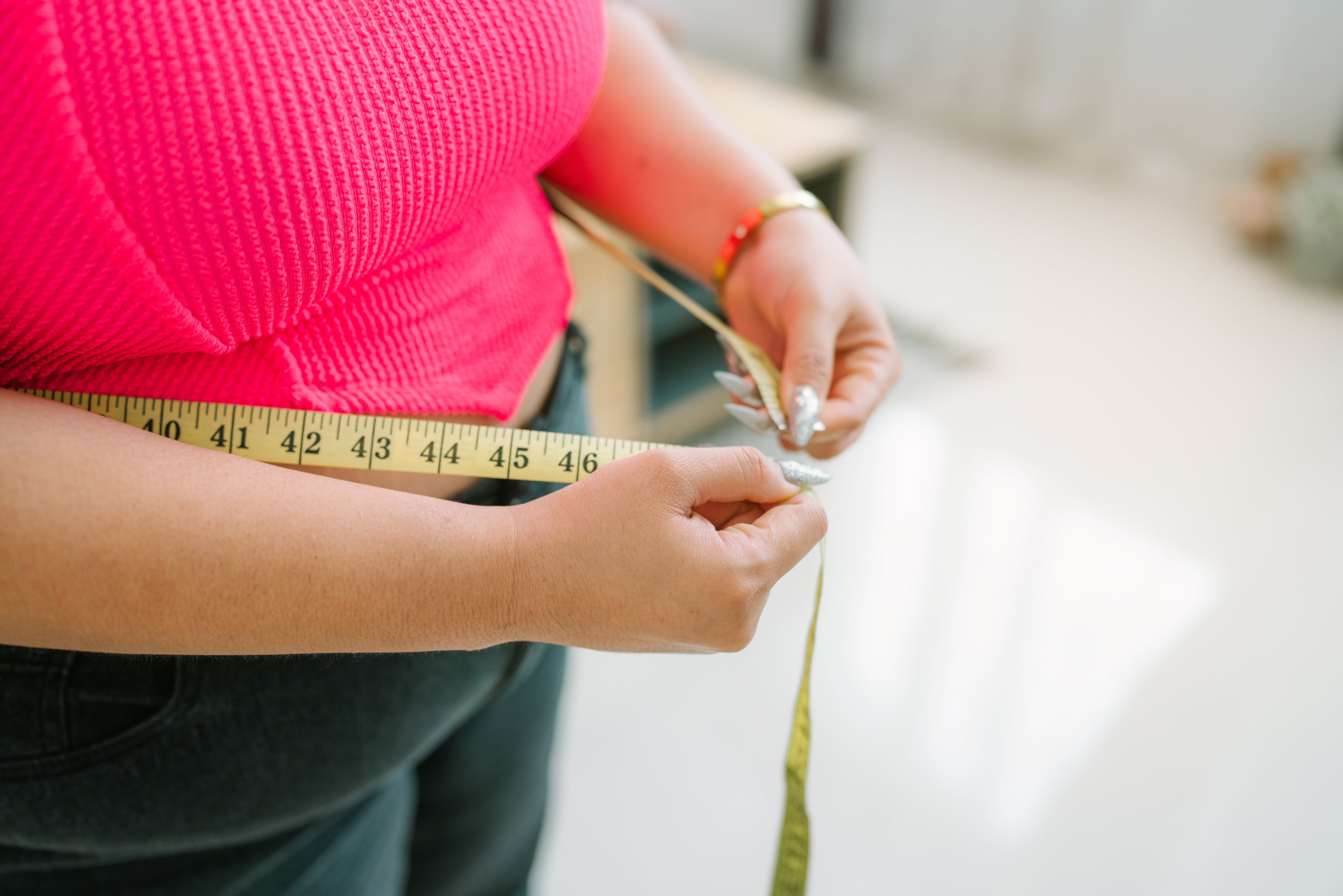 A woman measures her stomach. US obesity rates have fallen in the last few years, new data shows, possibly the result of new weight loss drugs hitting the market