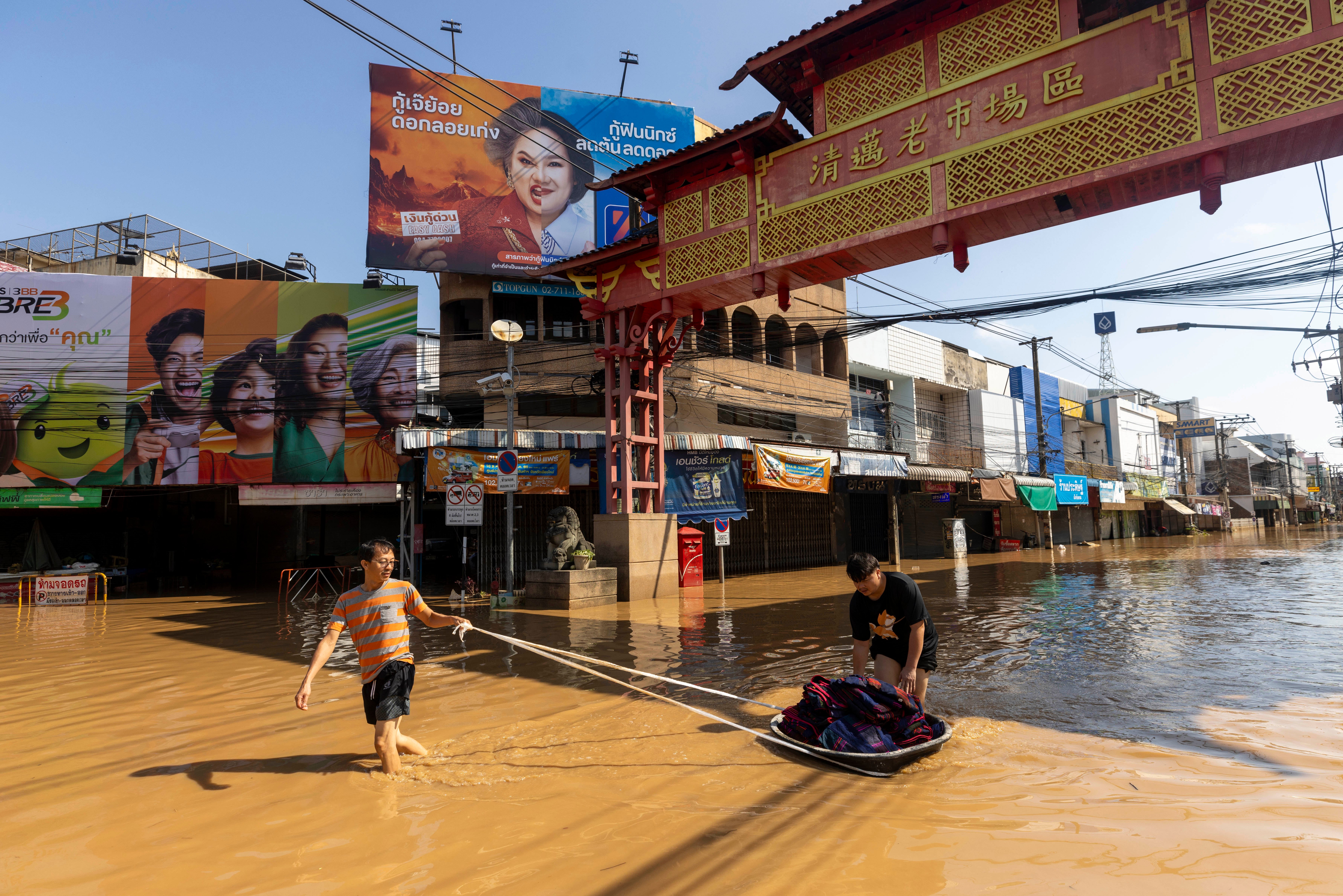 People drag their belongings through floodwaters in Chiang Mai Province, Thailand