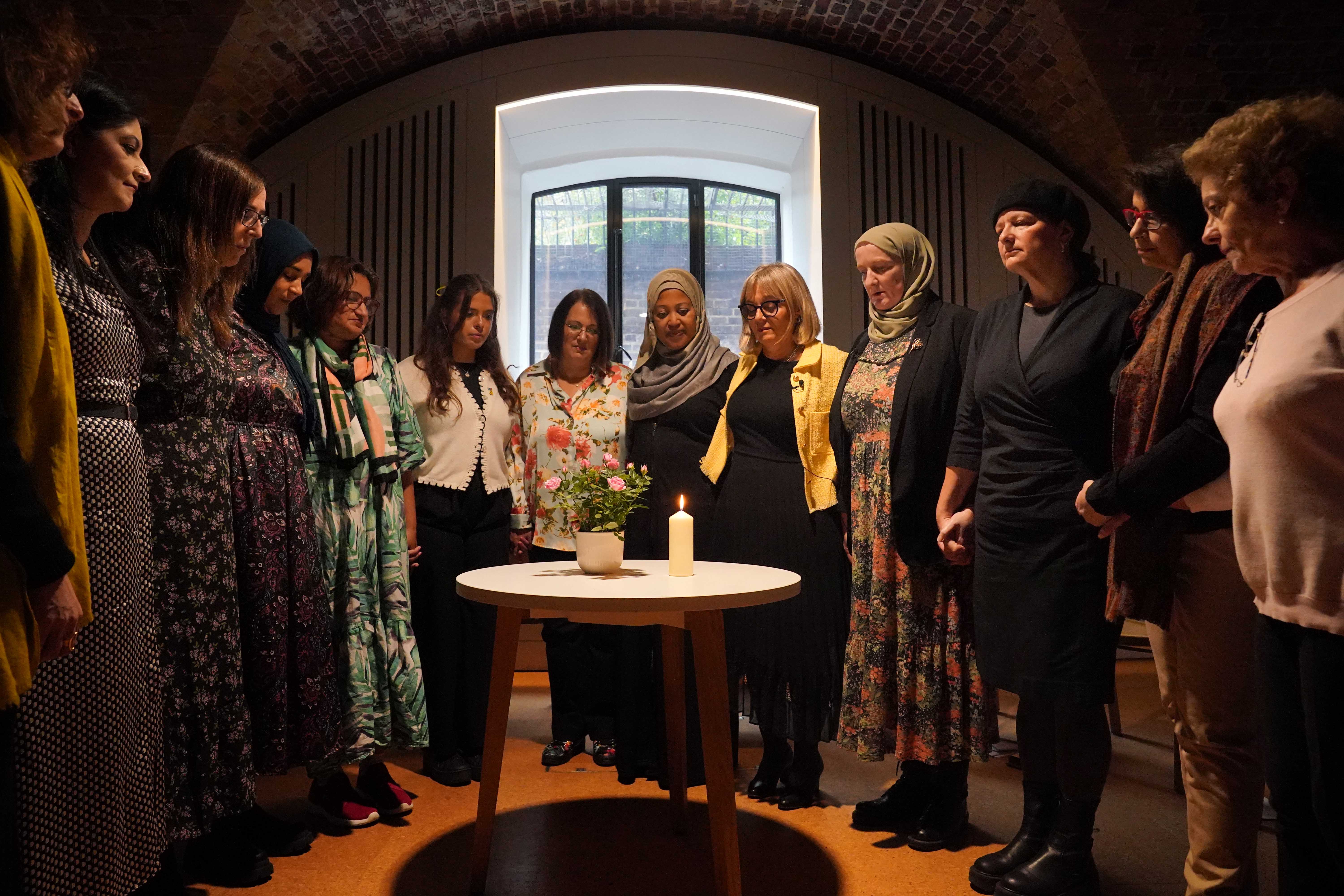 A group of Muslim and Jewish women during a minute silence after lighting a candle an event at St Johns Church, central London, to remember those who have died or are displaced and missing since 7 October