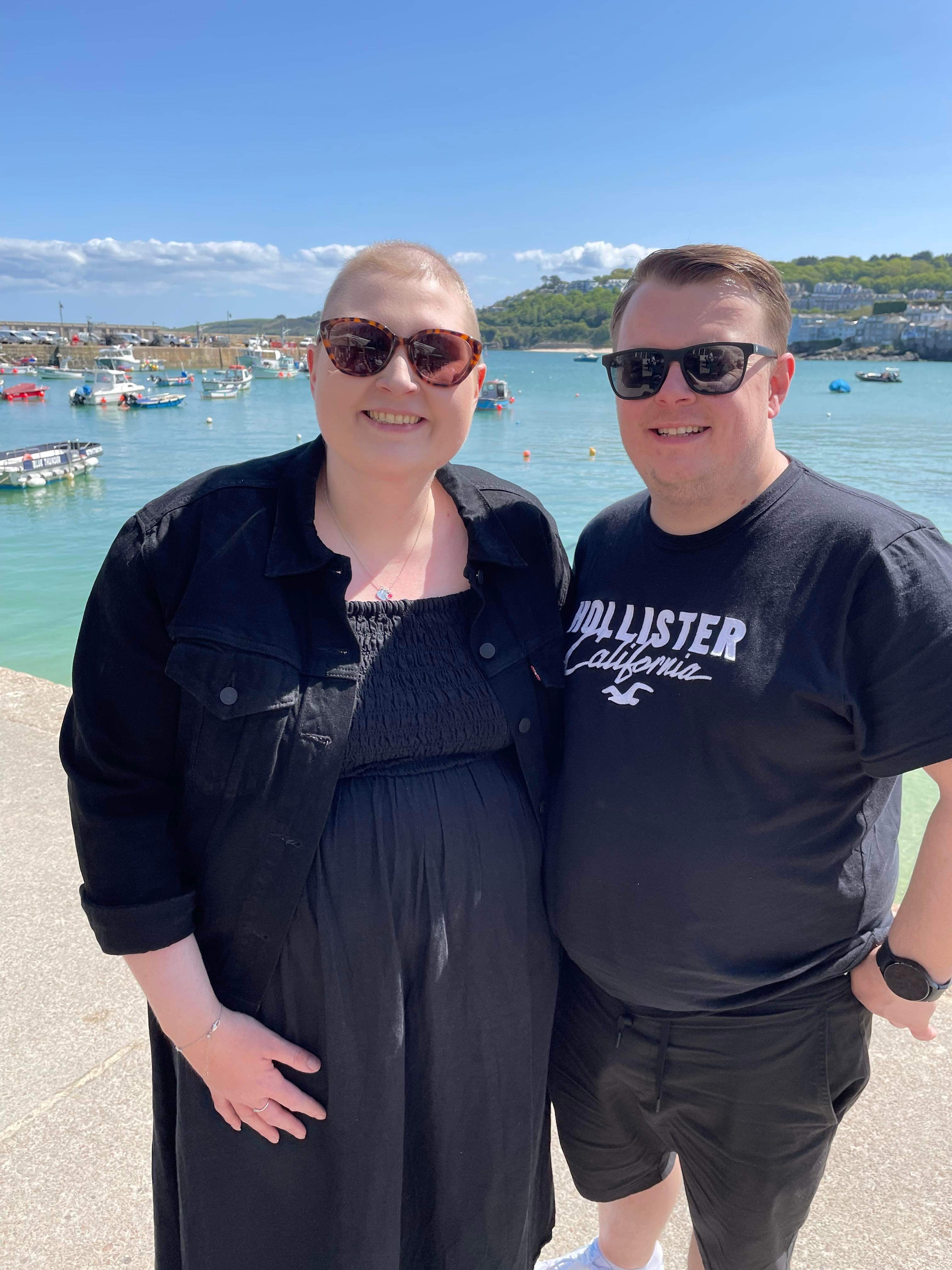 Jessica and Karl standing in front of a lake on a sunny day