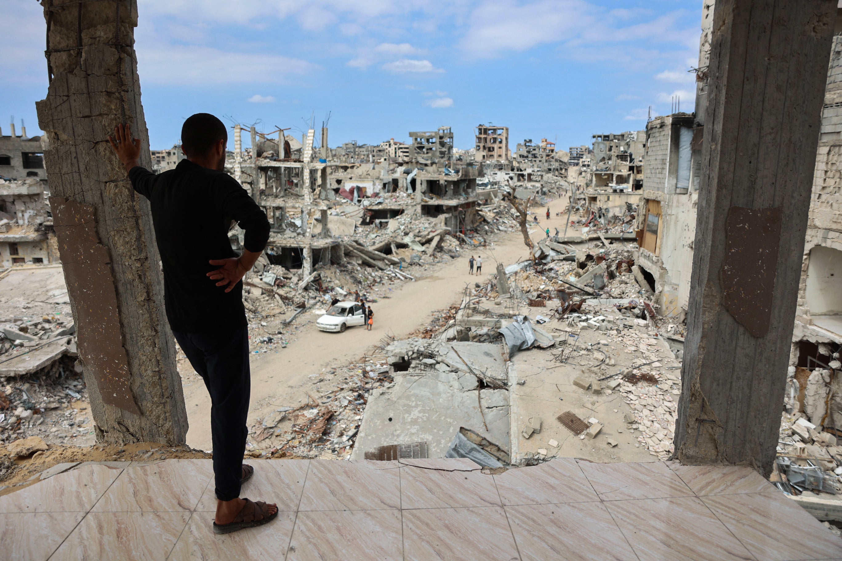 A Palestinian man looks from a damaged building at a road lined with rubble in the Shujaiya neighbourhood of Gaza City