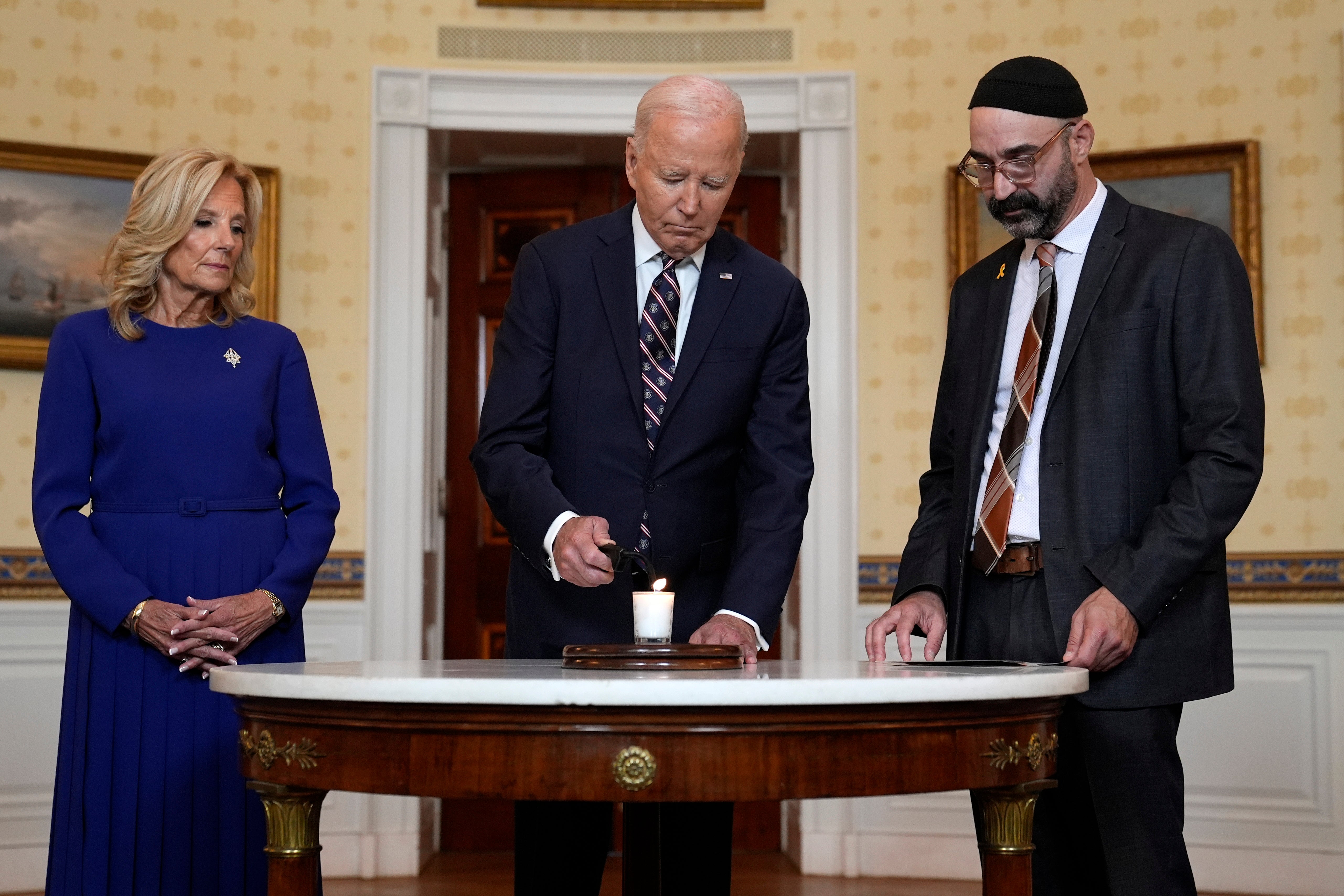 President Joe Biden standing with first lady Jill Bidenb and Rabbi Aaron Alexander of the Adas Israel Congregation, lights a memorial candle in the Blue Room of the White House to mark the one-year anniversary of the Hamas attack on Israel that left about 1,200 people dead